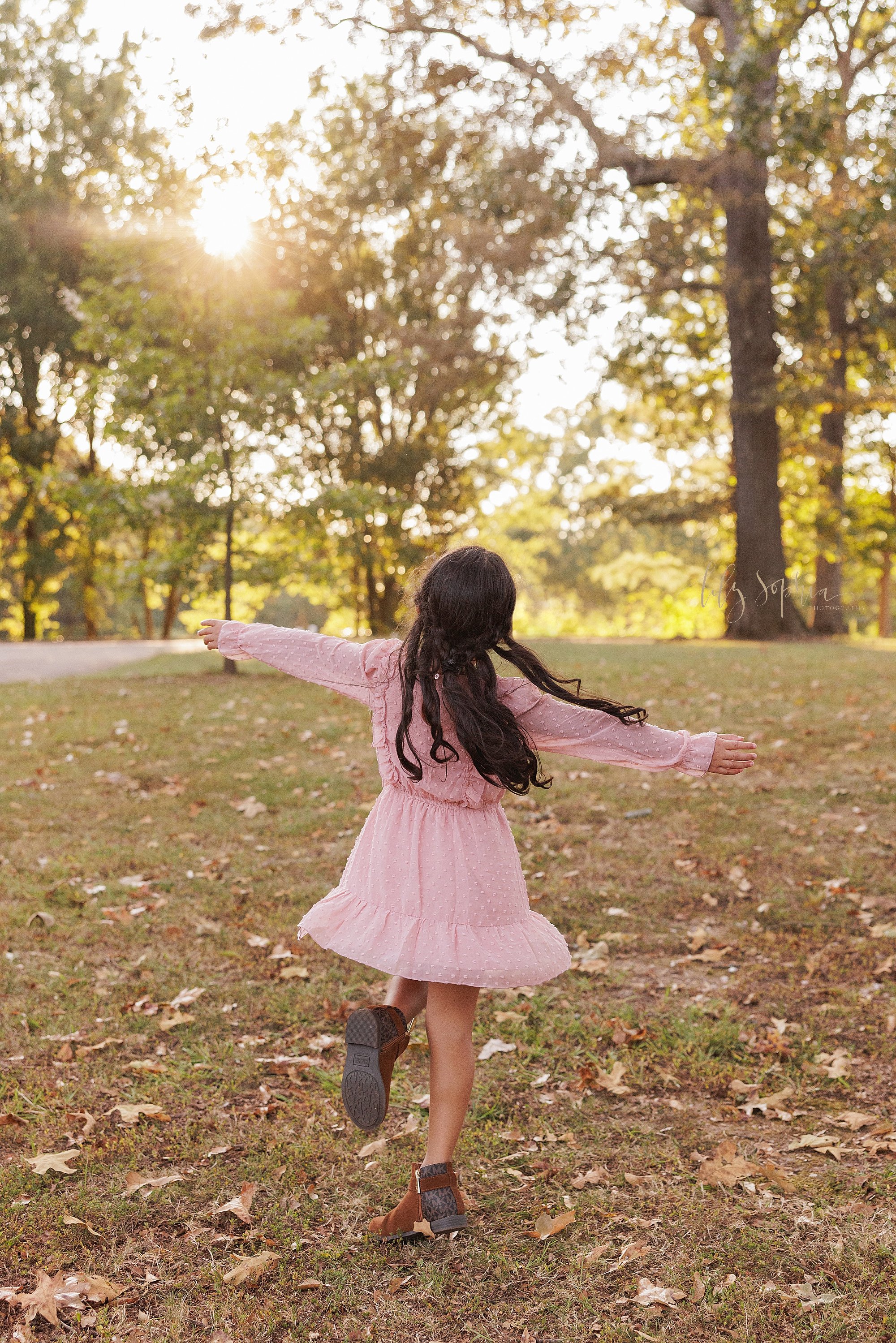  As a young girl freely twirls during autumn in an Atlanta park, her picture is captured at sunset for a family photo session. 