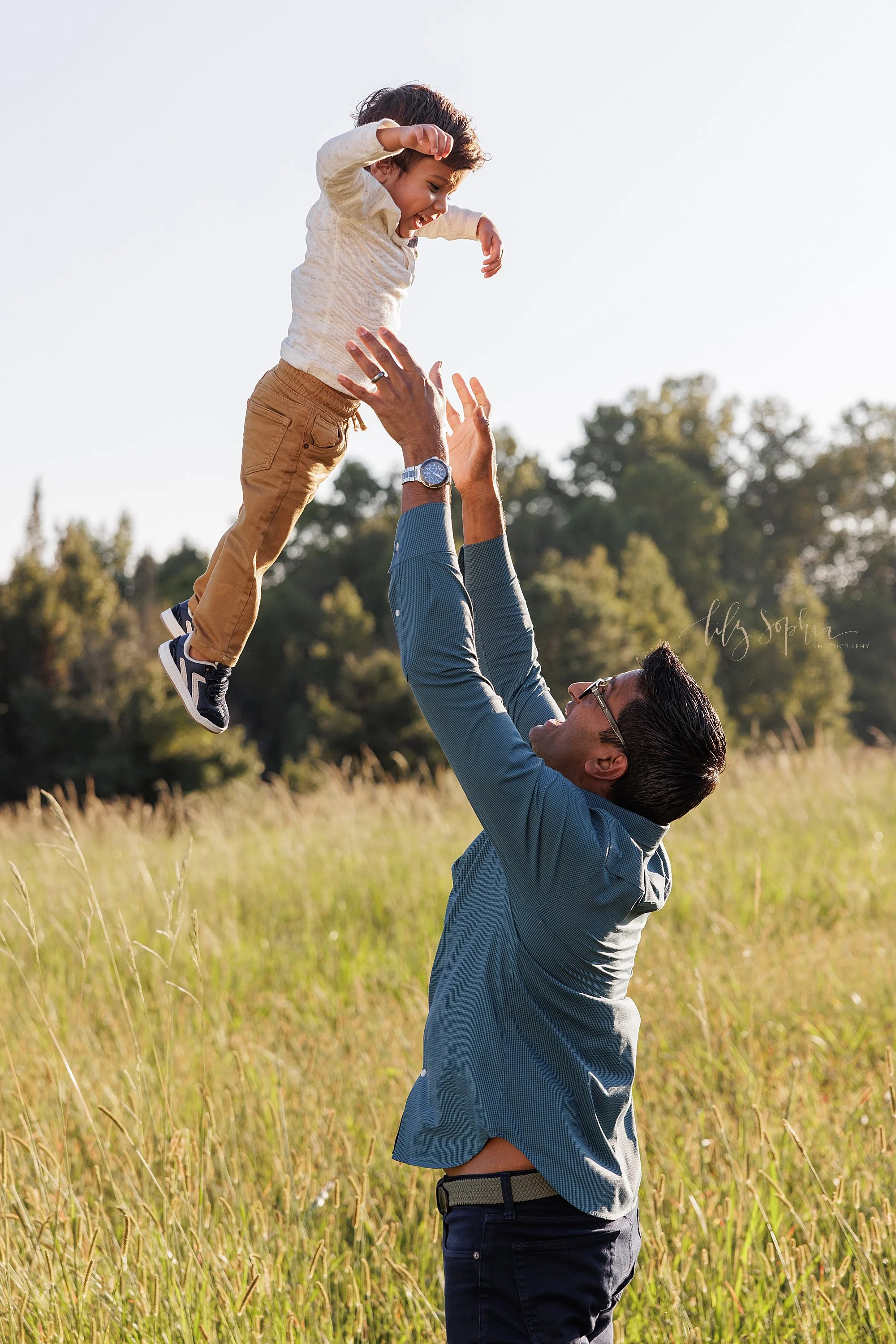  A father tosses his young son into the air as they stand in an Atlanta field during autumn for a family session at sunset. 