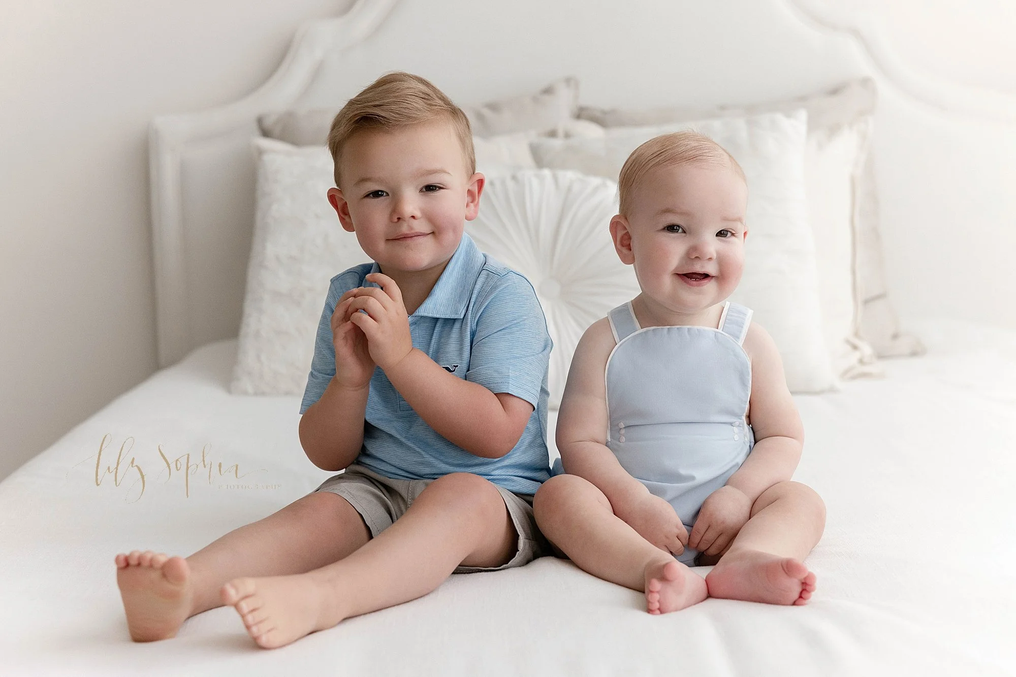  Sibling photo of brothers as they sit next to one another on top of a bed in a natural light photography studio near Oakhurst in Atlanta. 