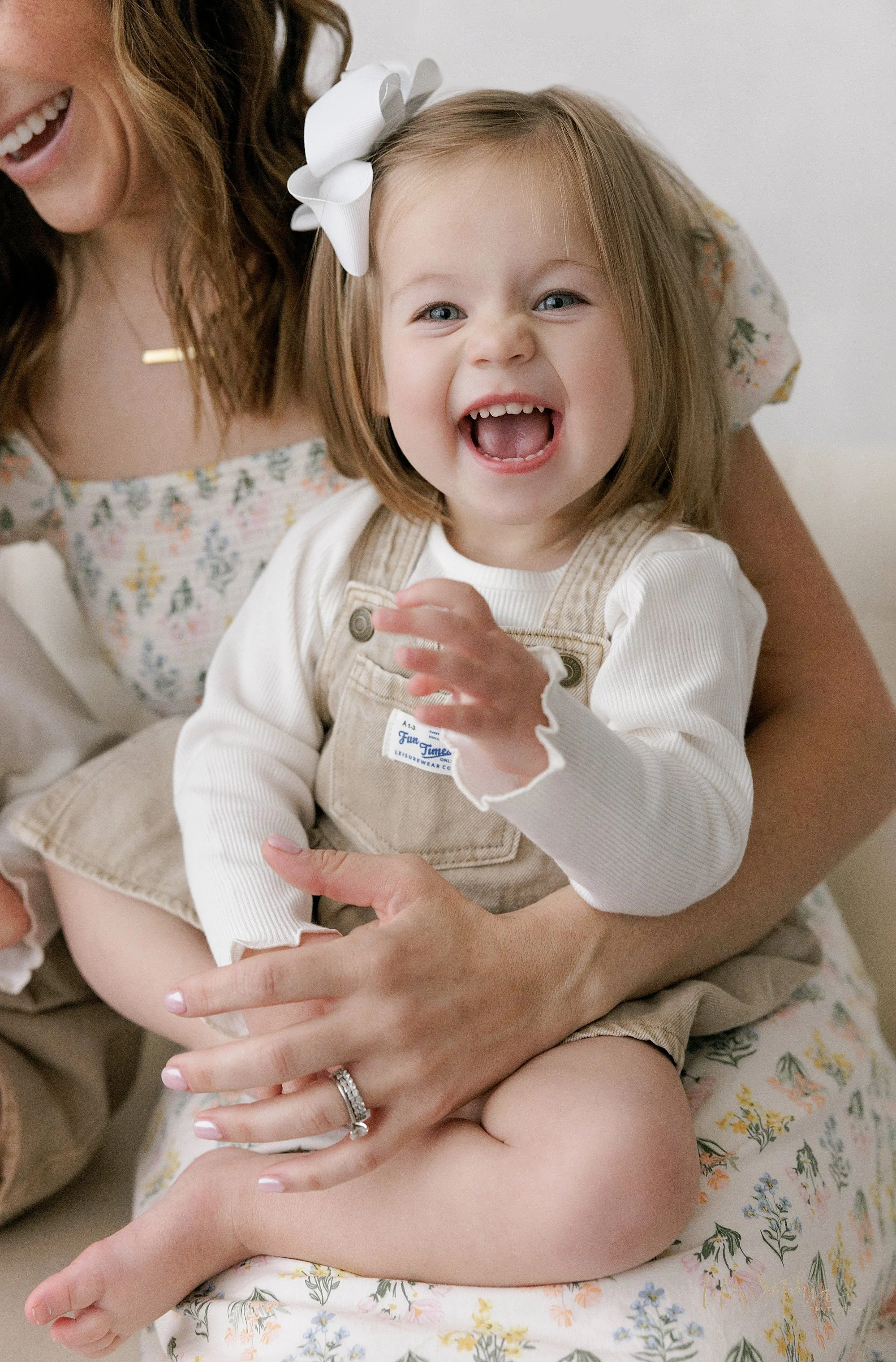  Close-up of a young girl as she sits on her mom’s lap and laughs taken near Decatur in Atlanta, Georgia in a photography studio at uses natural light. 