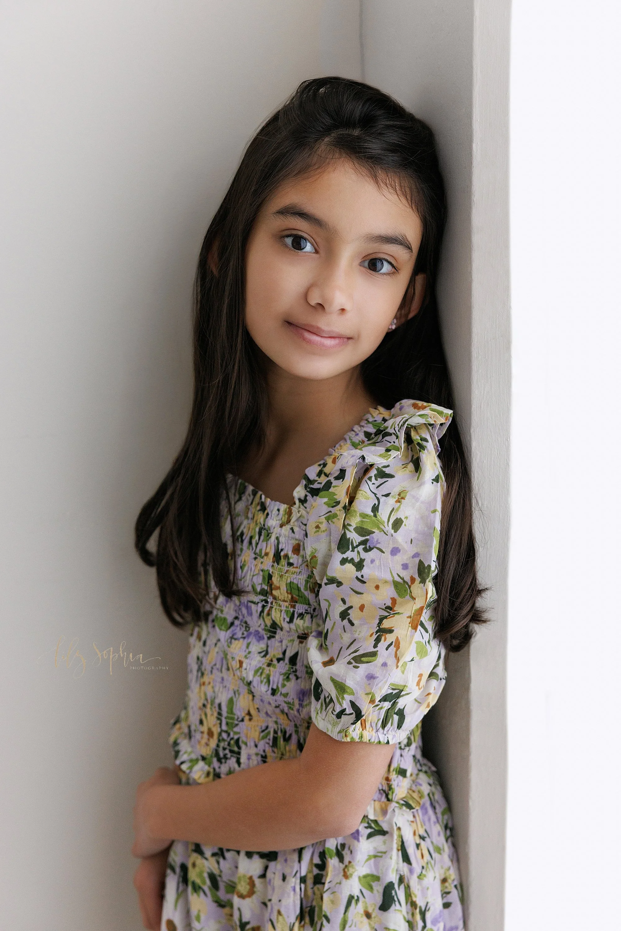  Portrait of a young girl as she stands in the corner of a photography studio that uses natural light near Decatur in Atlanta, Georgia. 