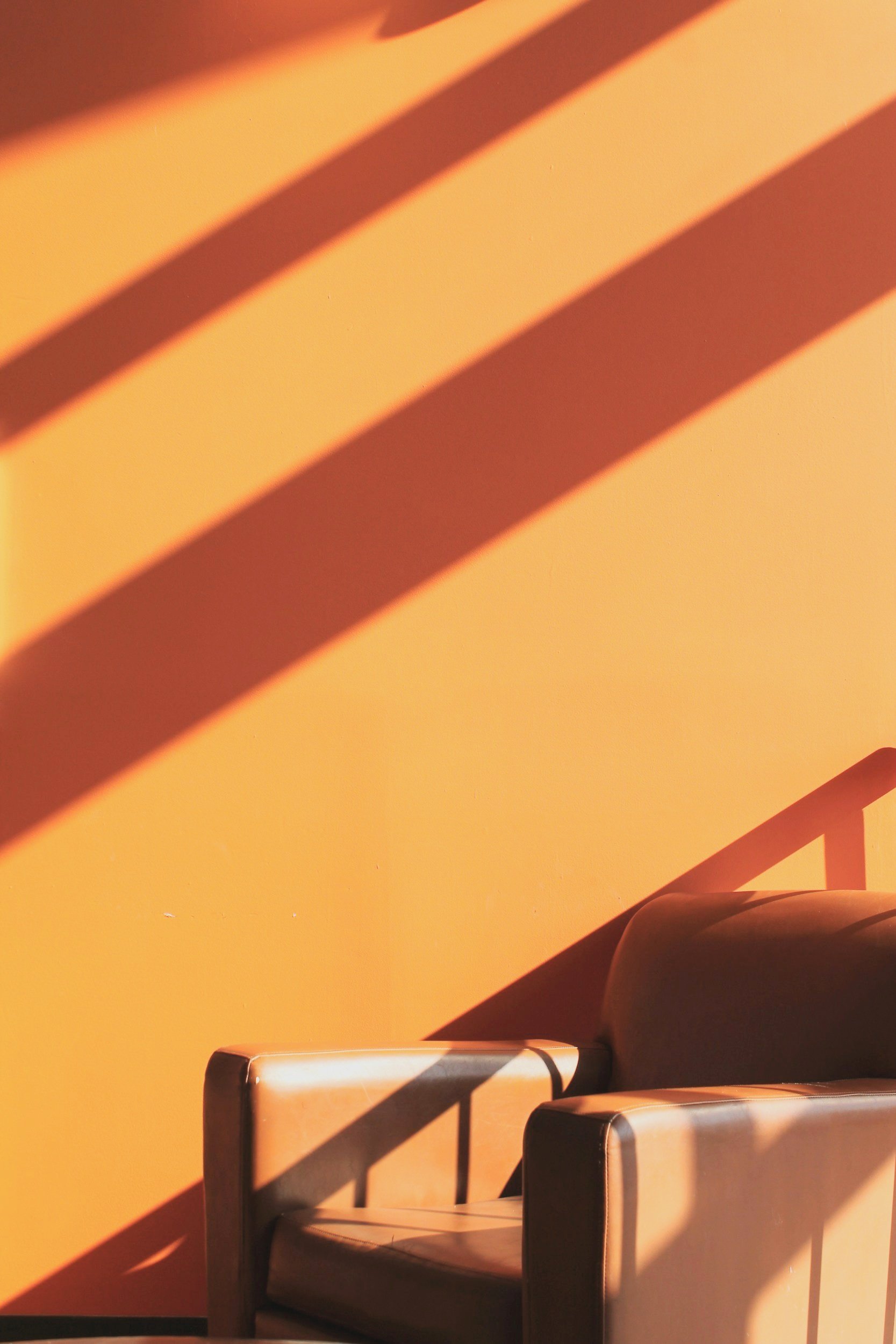 Brown armchair against an orange wall with shadows