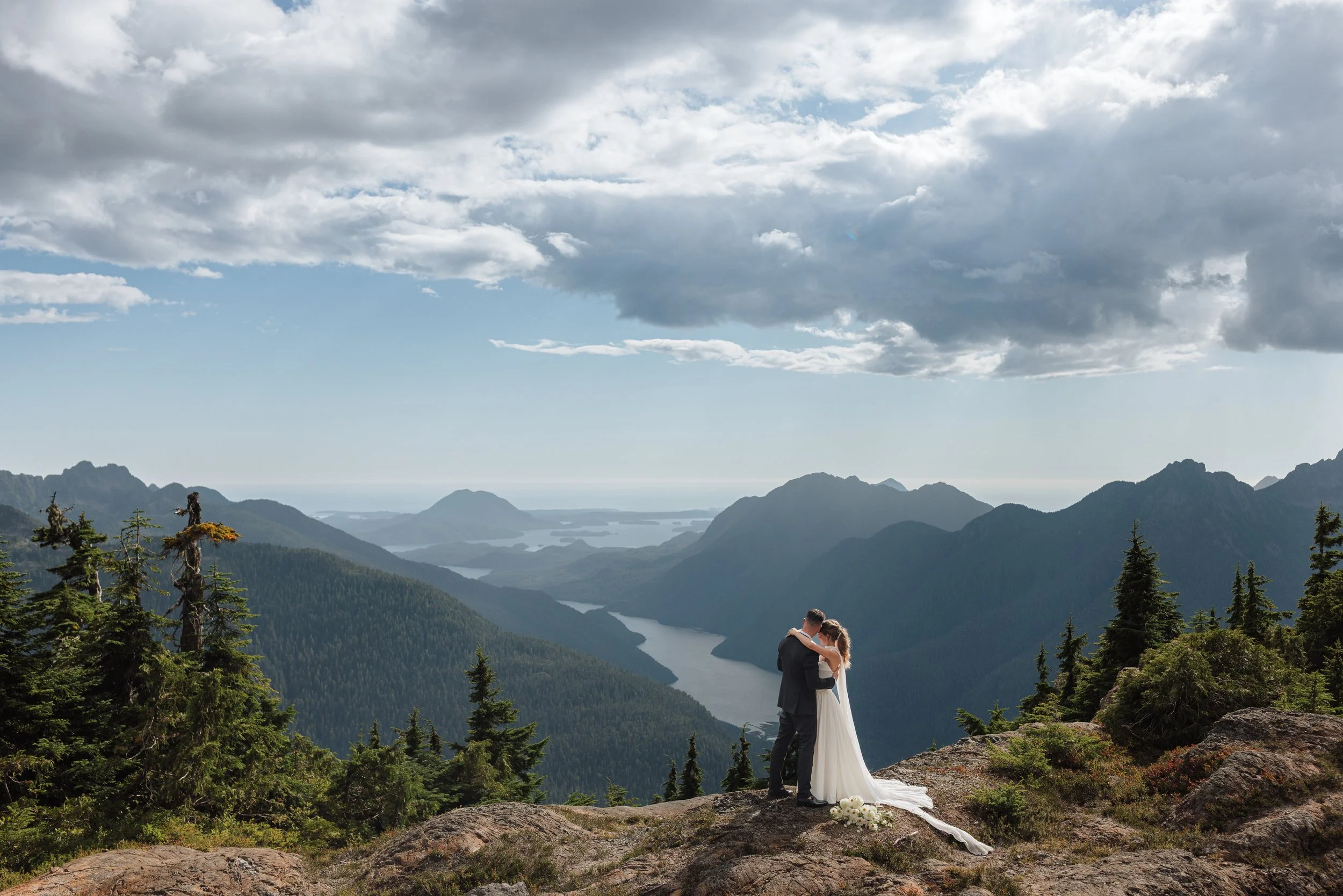 elopement couple hugging on mountain top overlooking Clayoquot Sound for their Tofino Helicopter Elopement