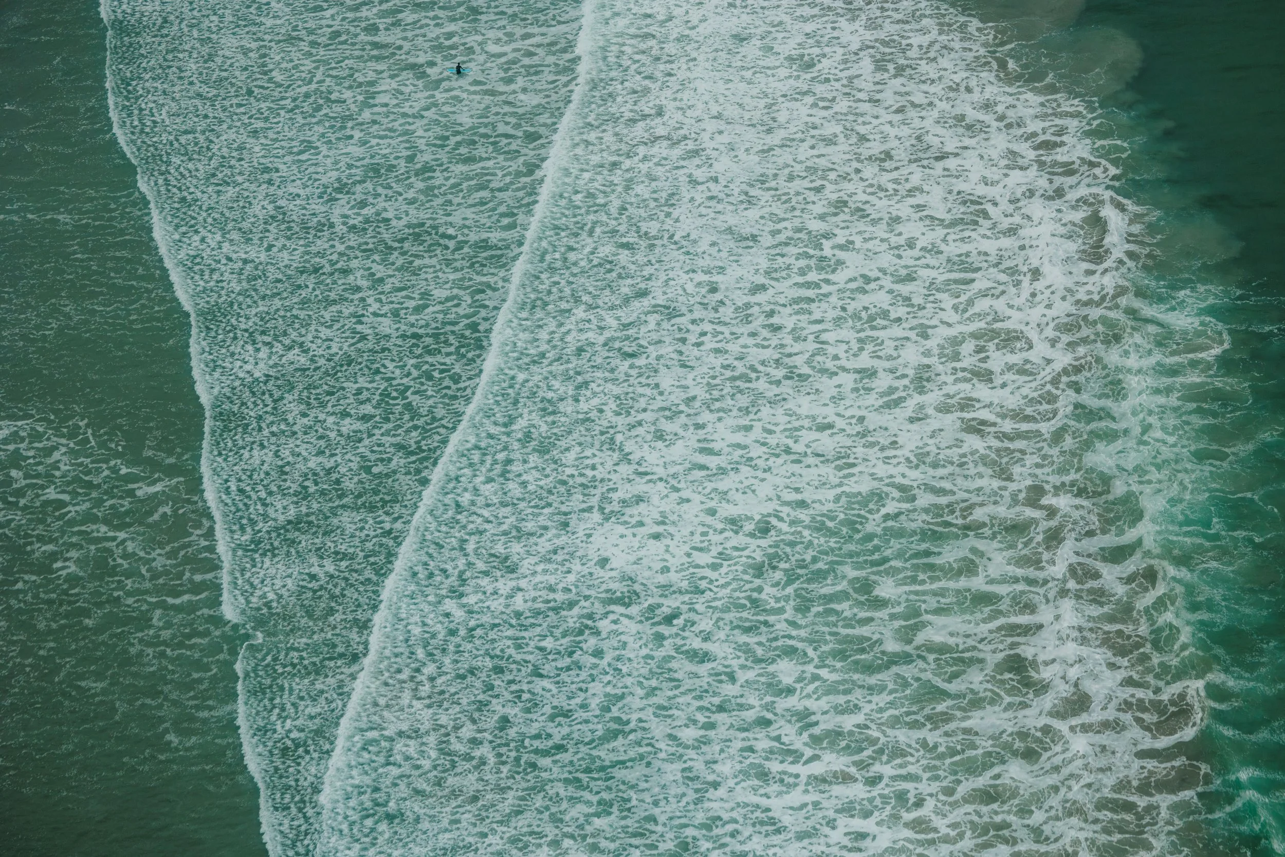 Aerial view of ocean waves with surfers in Tofino, BC