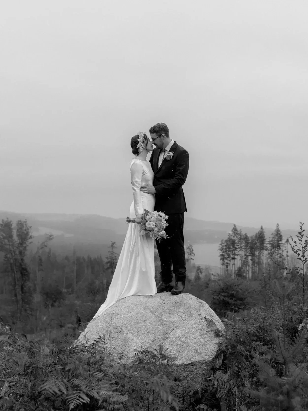 wedding couple standing on a rock with a misty mountain and forest backdrop on the sunshine coast bc