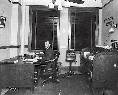 A.R. Wilson at his desk in the ALICO building . Image Source.