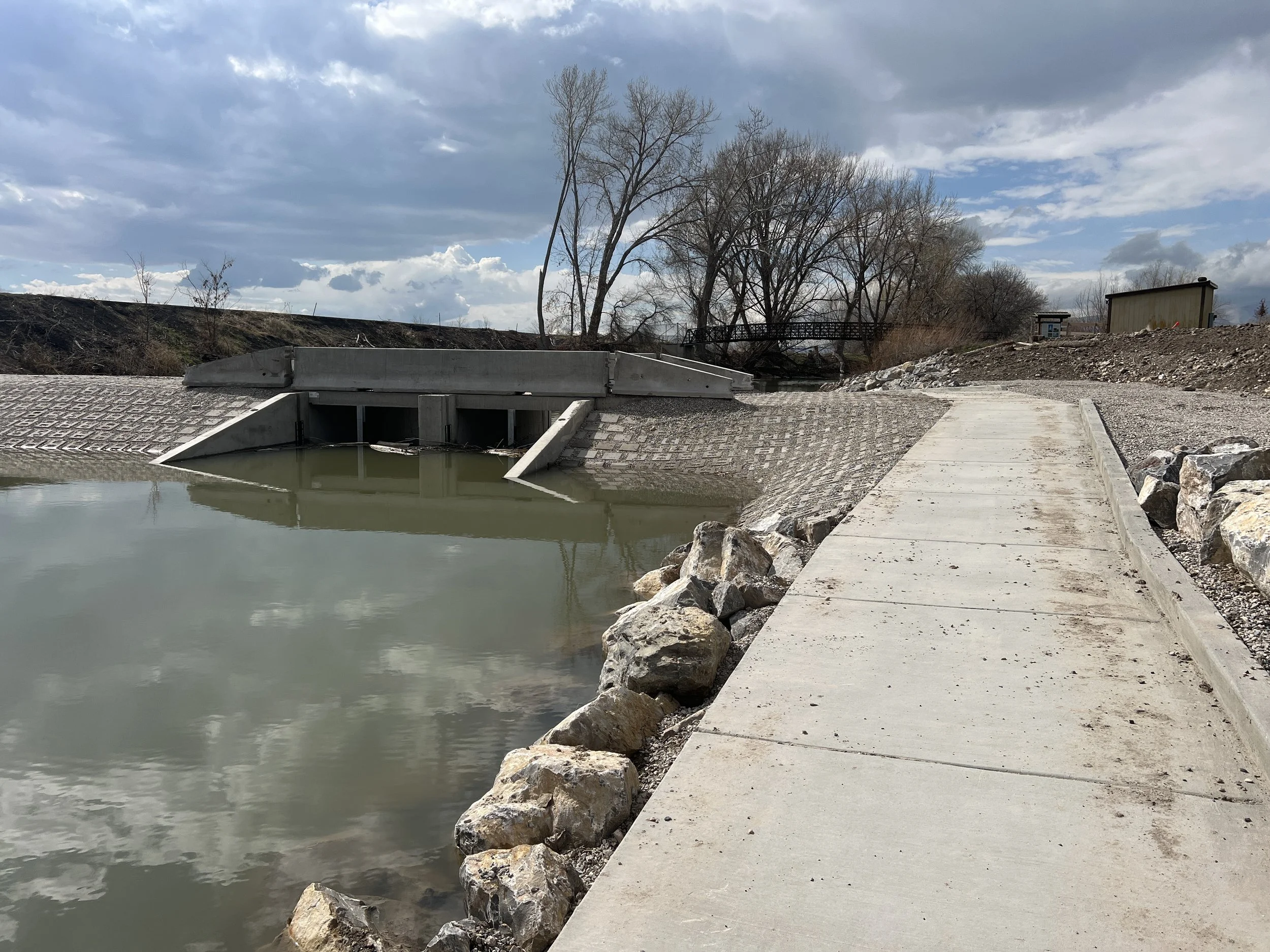 Small dam with  portage sidwalk and bride across the channel in the distance