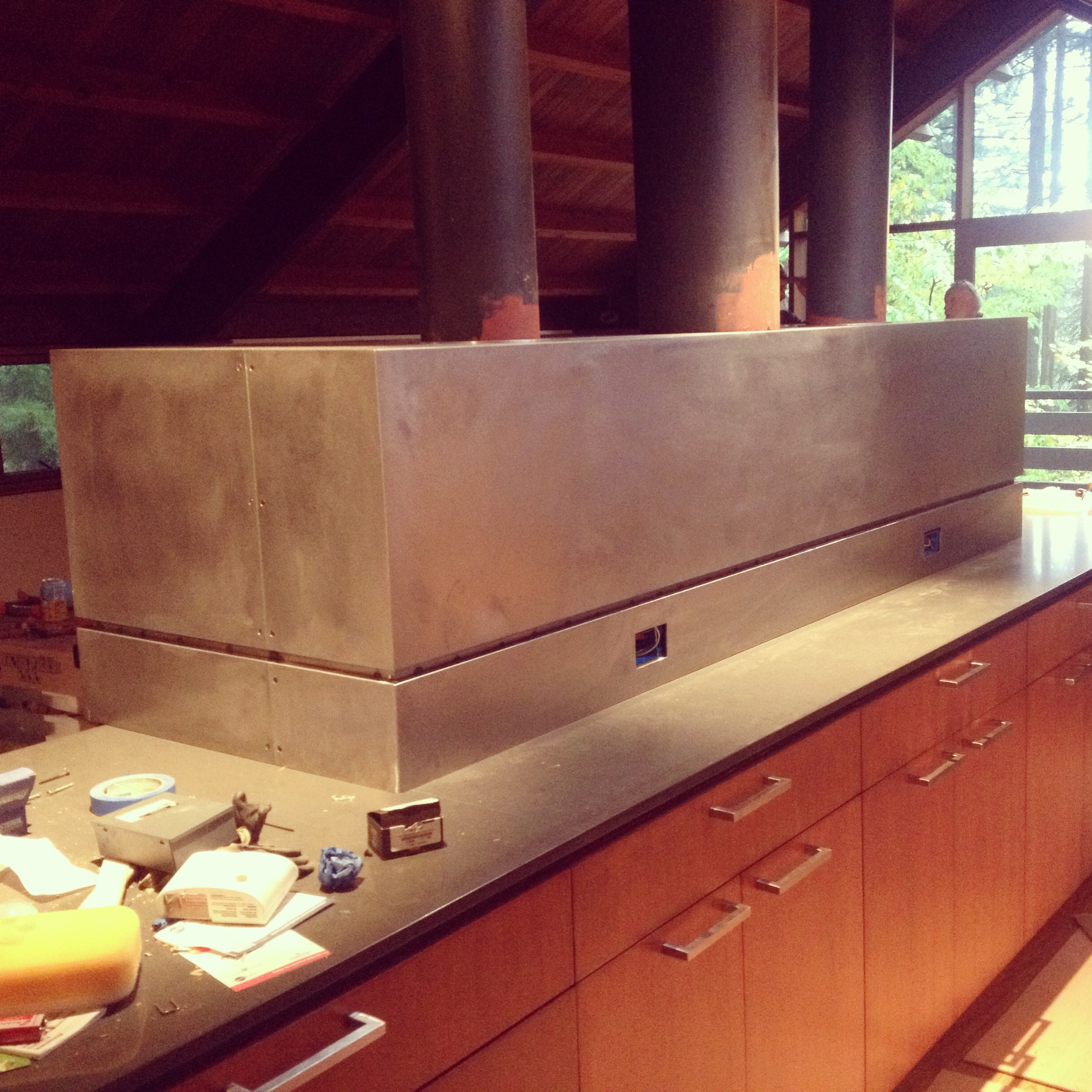  Steel cladding to cover the top of a fireplace and create a divide between the kitchen and living area. Outlets were cut in as well. Pictures are during construction.  Designed by Paul McKean Architecture 