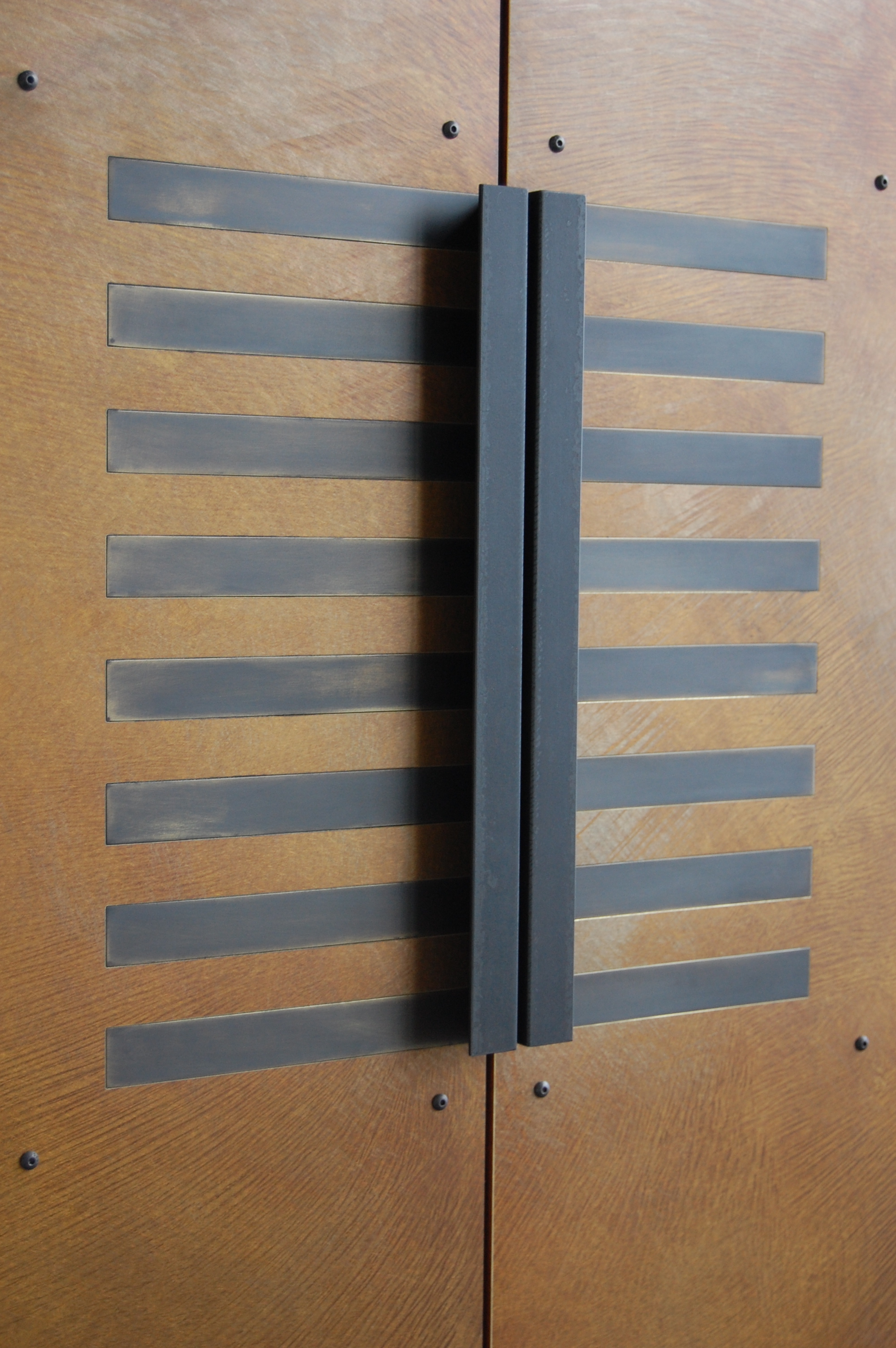  Cabinet doors with brass veneer with patina and blackened brass inlay. Custom steel handles.  Designed by Hensel Design Studios 