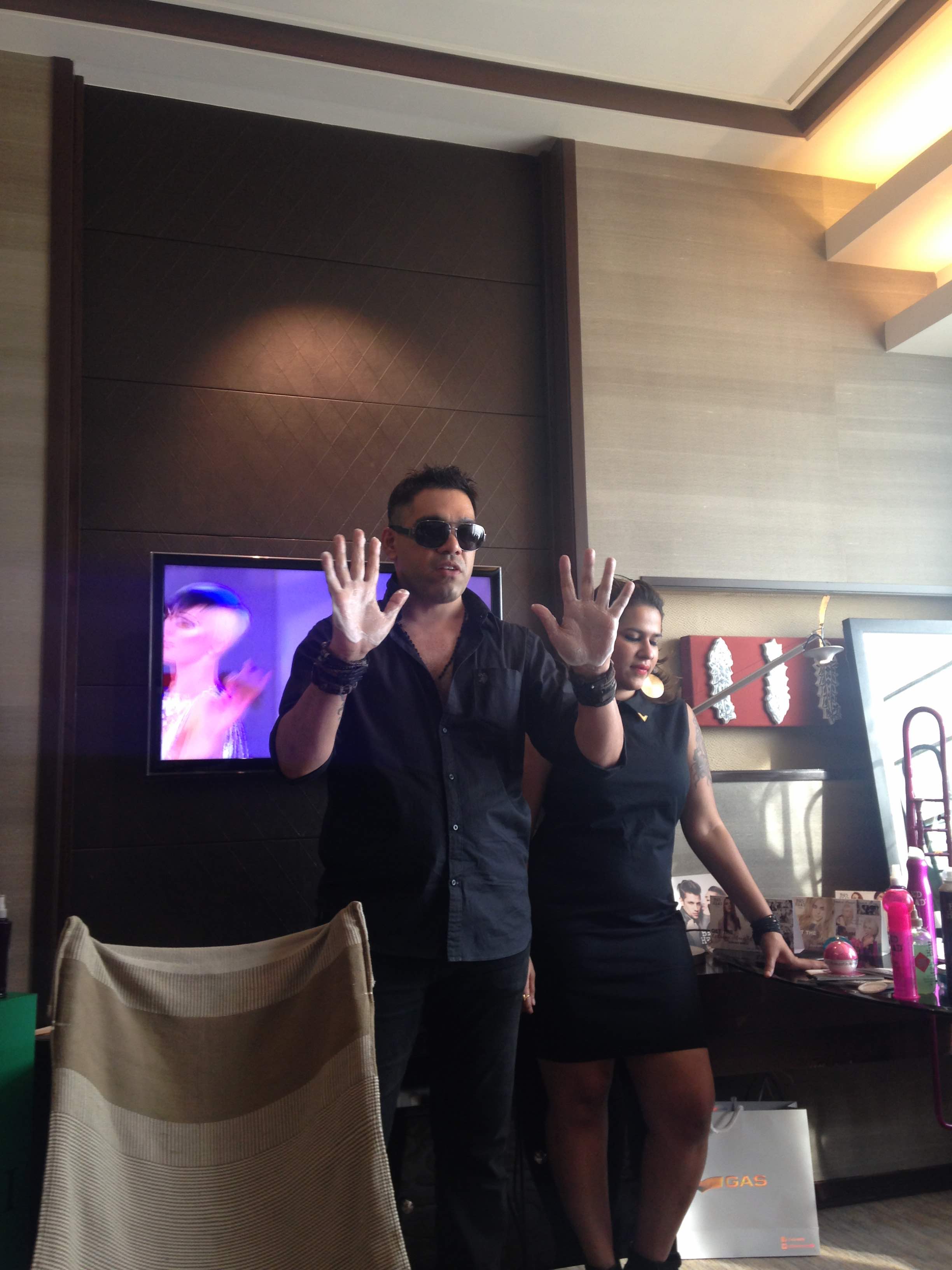 Savio John Pereira explaining the importance of putting the product in-between the fingers to apply to evenly throughout the hair. 