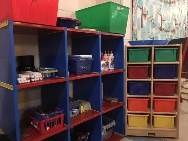 Colorful cubby shelves with various art supplies and storage bins.