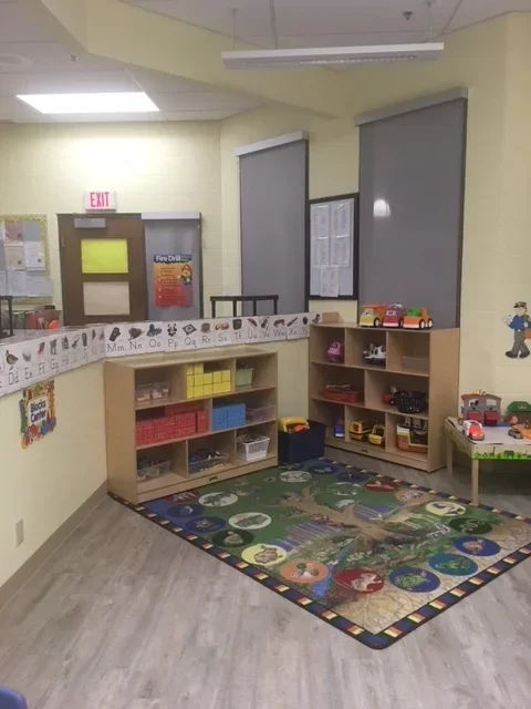 Children's play area with storage shelves, toys, and a colorful alphabet-themed rug.