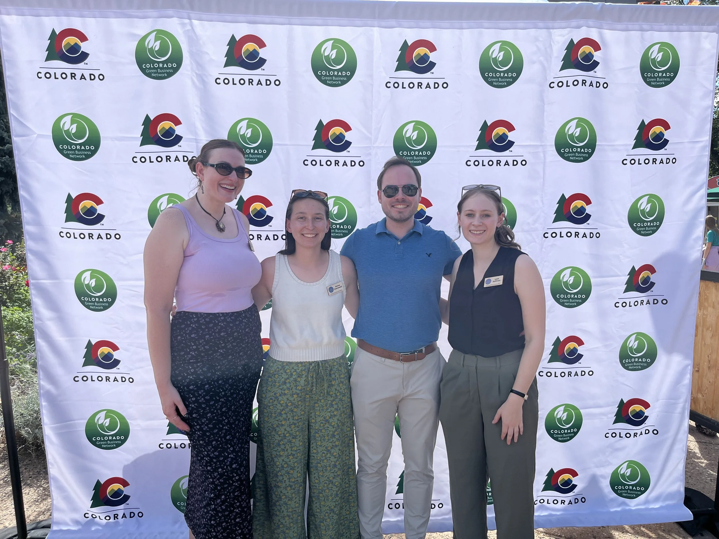 Four Lotus staff posing in group photo with a white back drop outside.