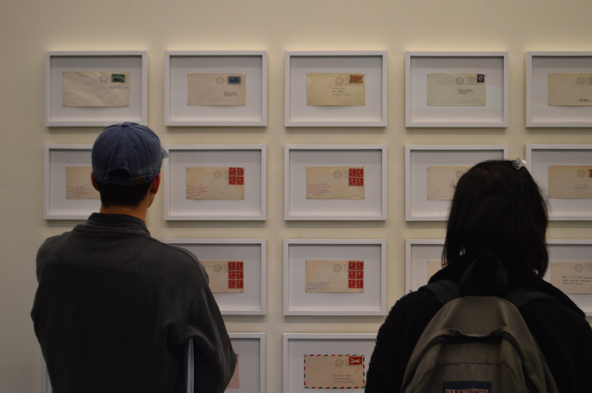 “Students gaze at handwritten postcards through glass”