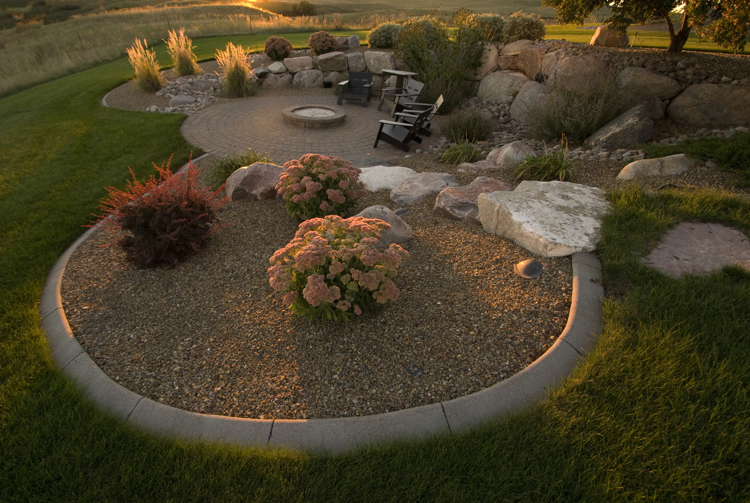  Boulder steps and flagstone lead guests to a patio and firepit surrounded by wock beds with shrubs and&nbsp; 