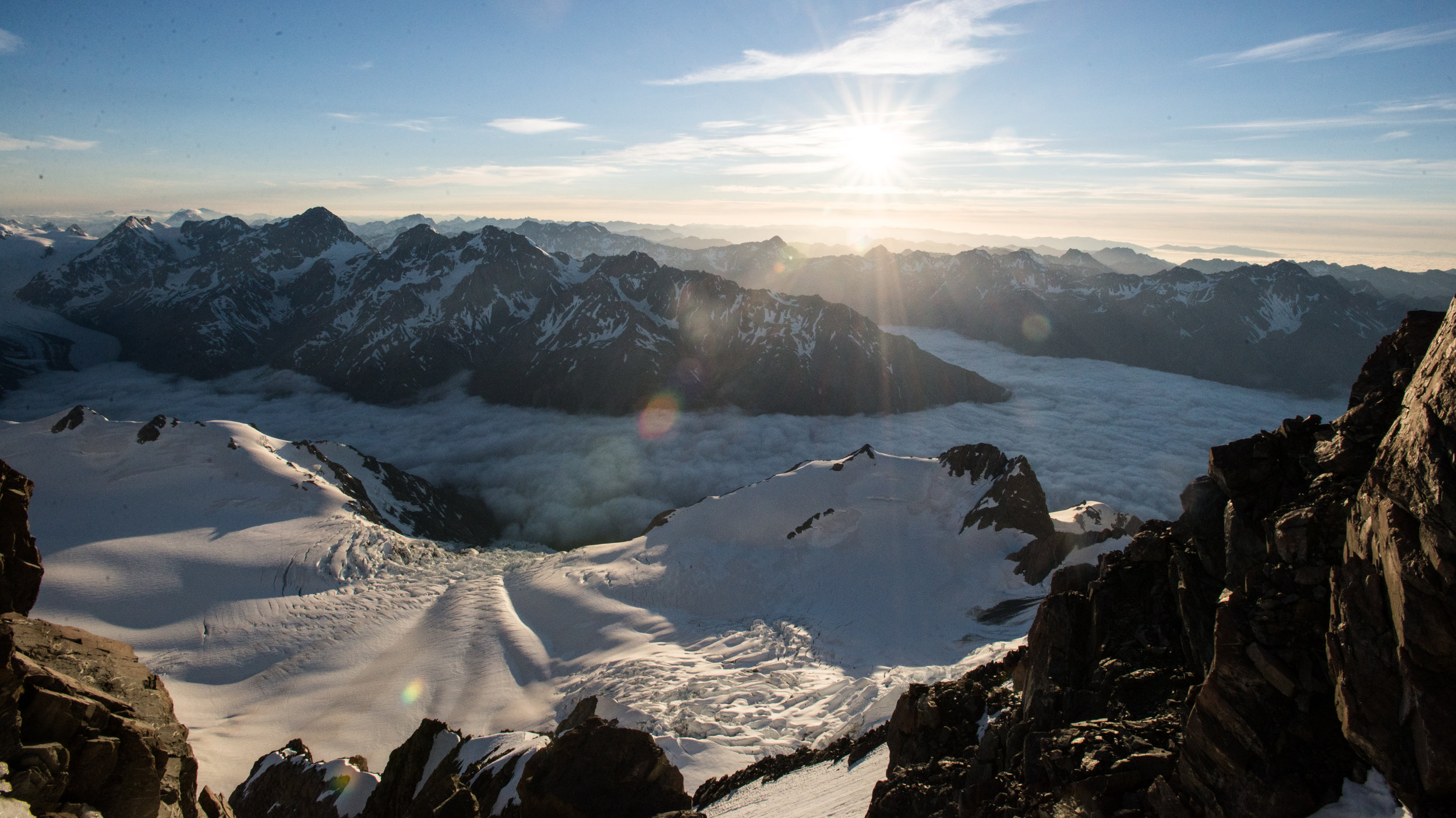 Just below the Summit rocks, the Grand Plateau with the Plateau hut visible on the sunny ridge to the left