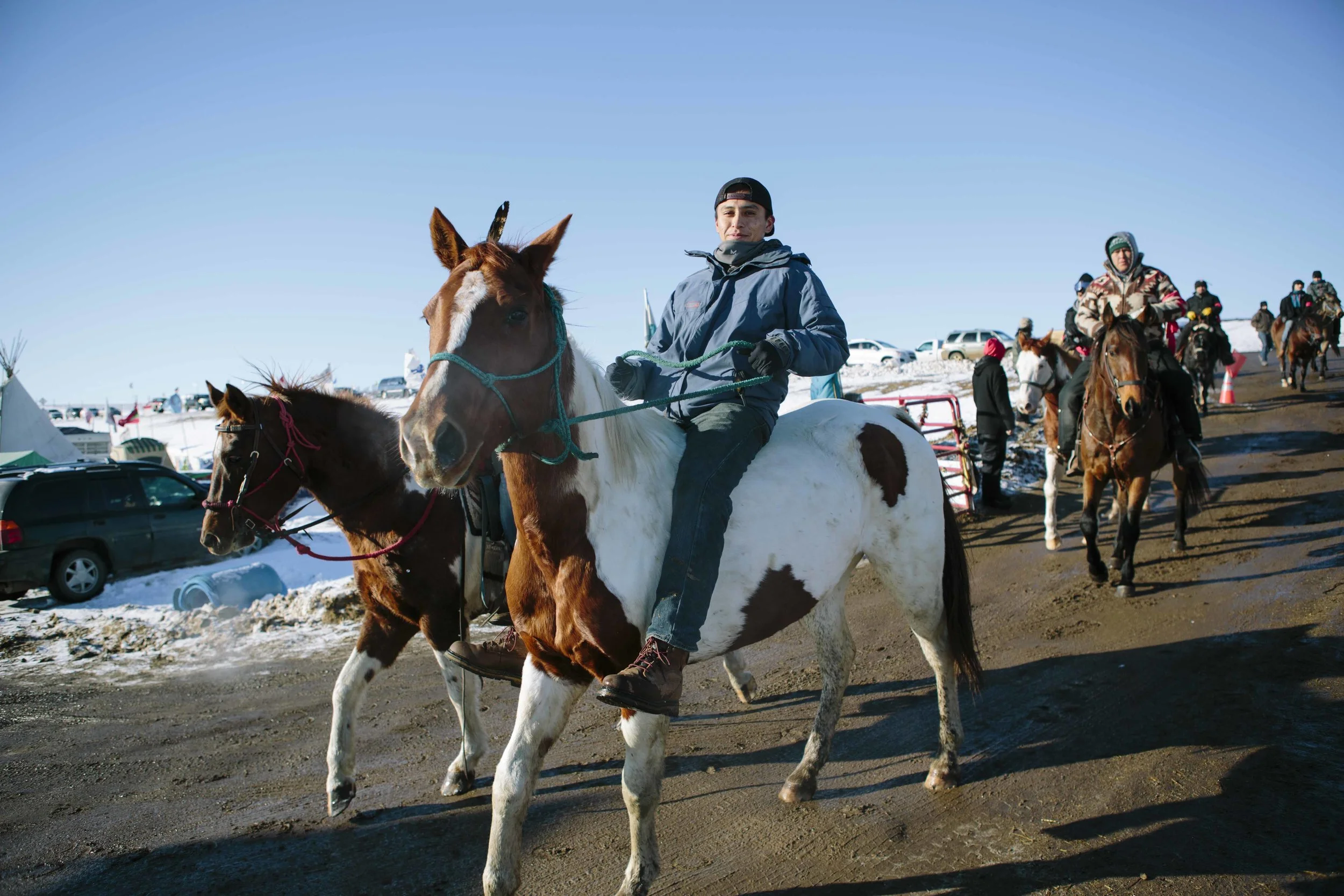 Lakota tribesmen enter Oceti Sakowin on horseback