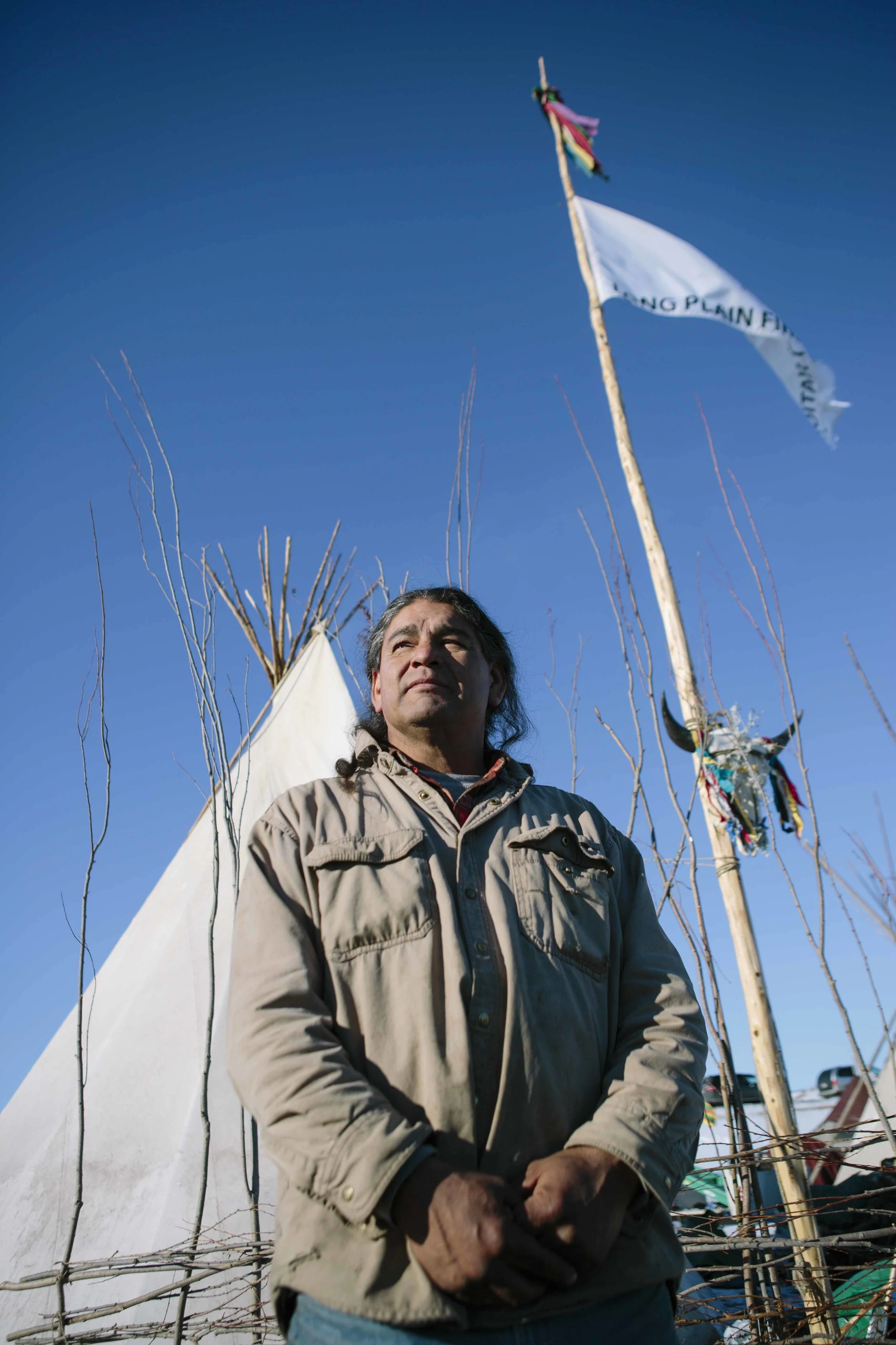 Matthew Black EagleMan stands in front of his teepee encampment named Red Road Awareness
