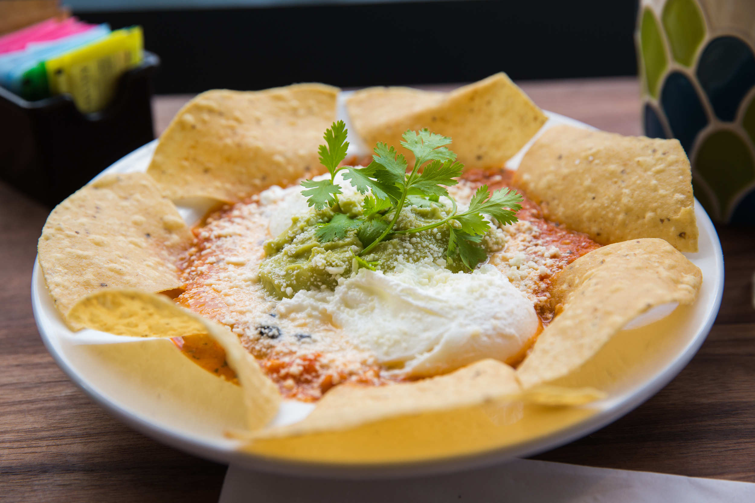 Huevos Rancheros - Poached Eggs, Salsa, Avocado Mousse, Black Beans, Cheddar & Cotila Cheese, Tortilla Chips