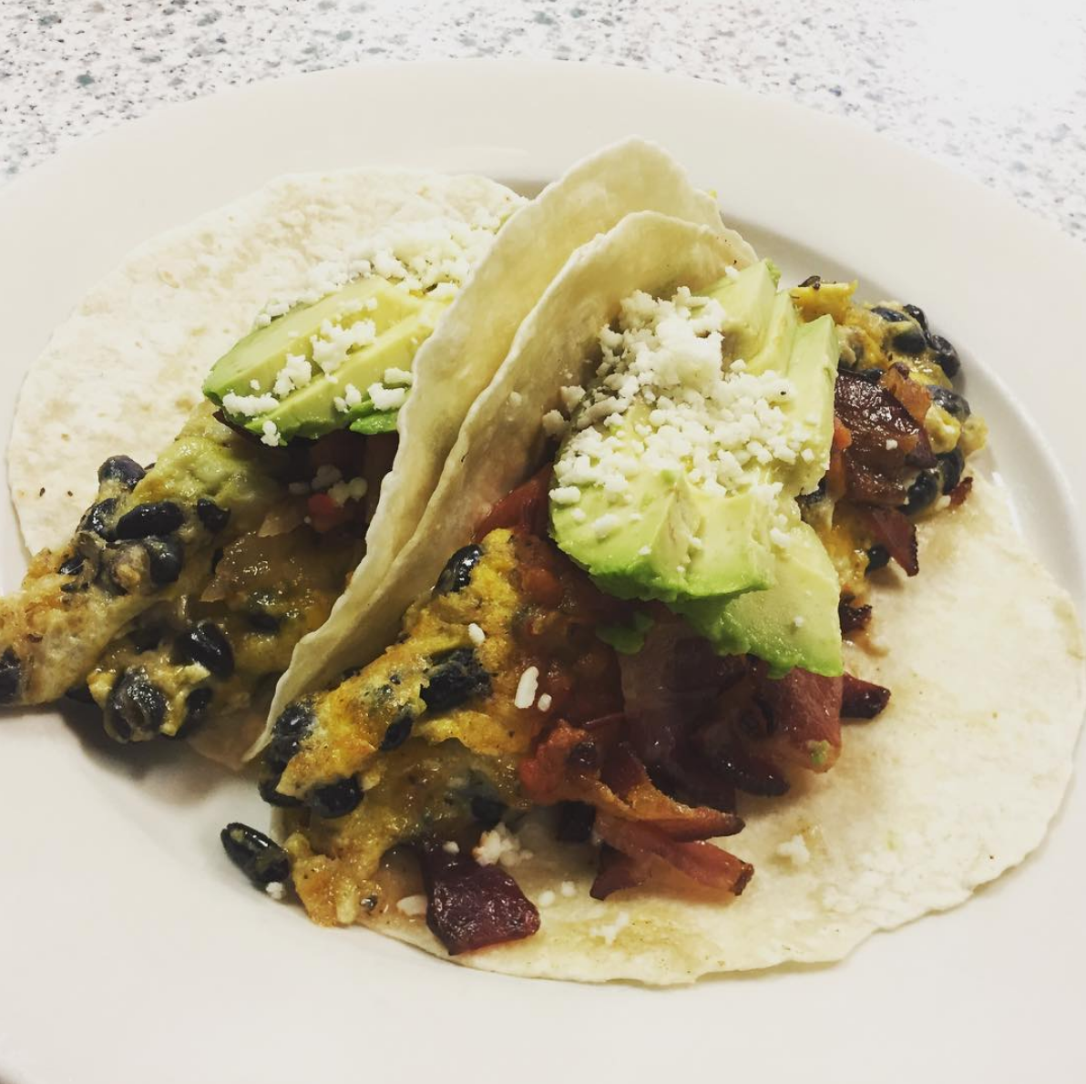 Breakfast Tacos - Corn tortillas filled with scrambled eggs, bacon, black beans, avocado, and cotija cheese