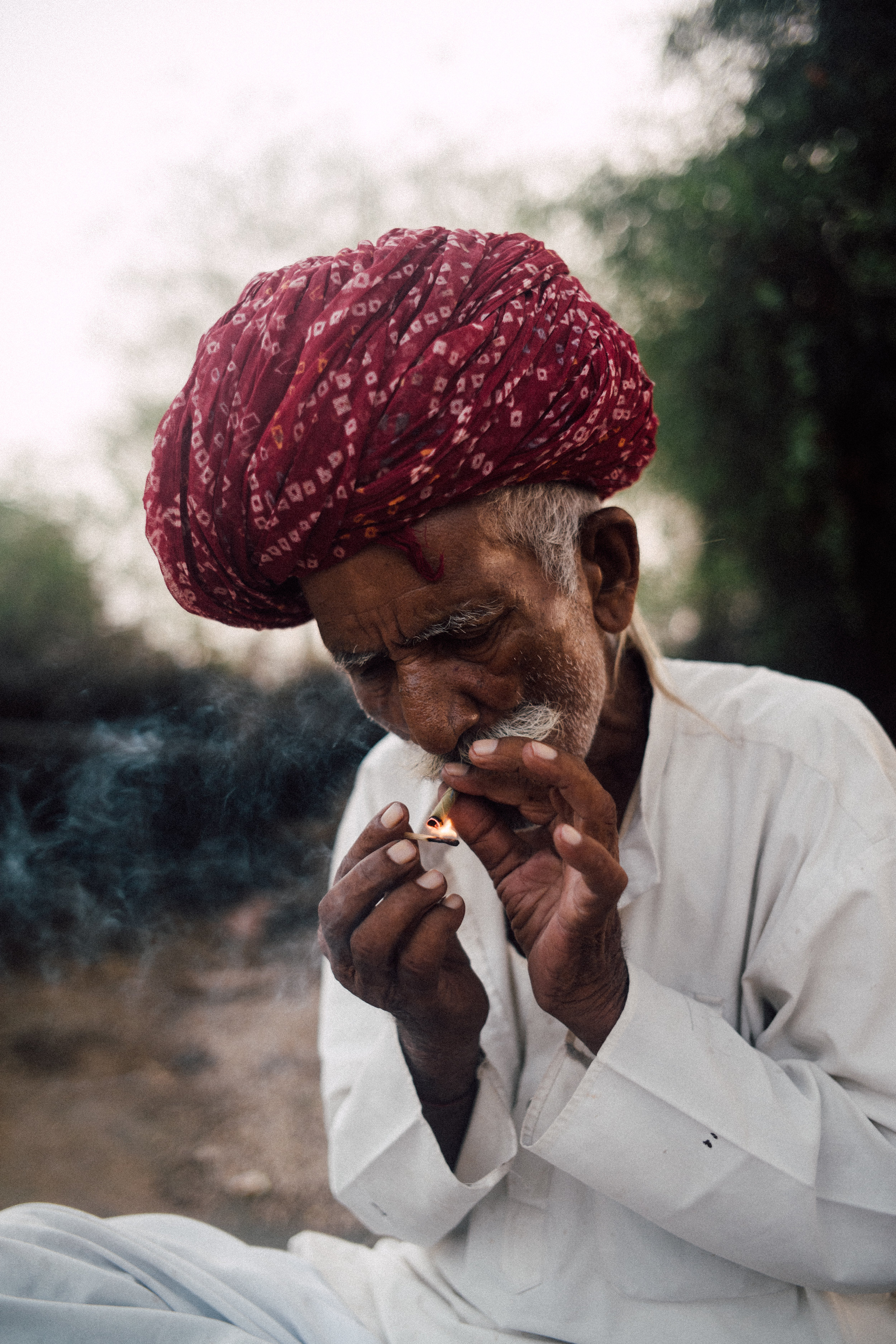 A Bishnoi village local roles and lights a cigarette as the sun behind him sets.