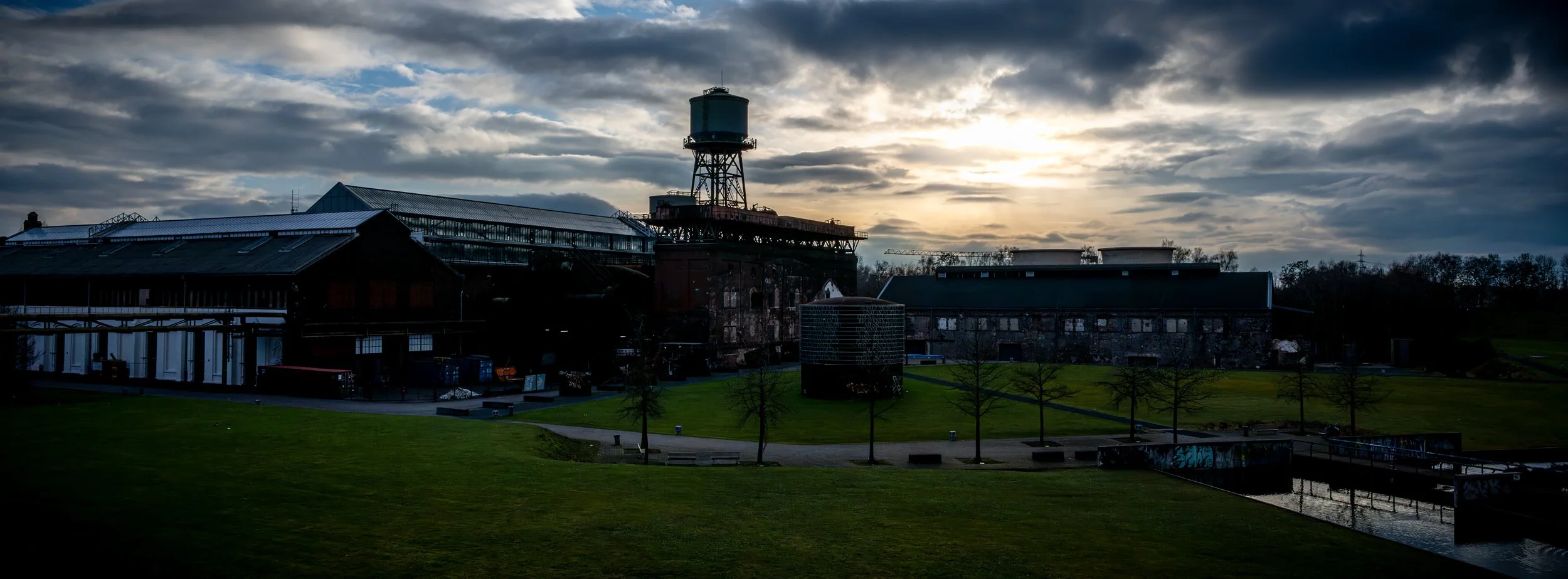 Gebäude und Wasserturm des Bochumer Westparks vor dramatischem Himmel.