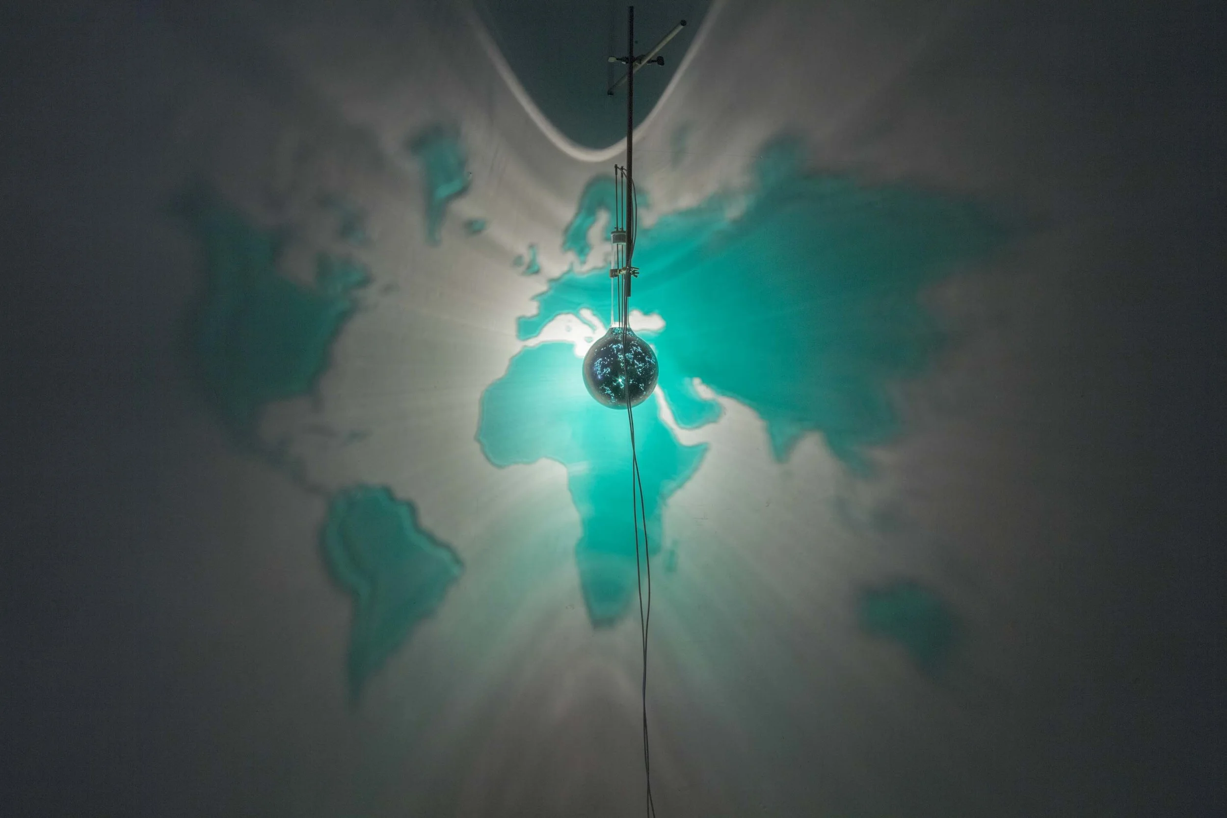 Mondo Smeraldo , 2010, painted laboratory bottle, laboratory pliers, halogen lamp bottle diam. 16 cm, image 250x180 cm