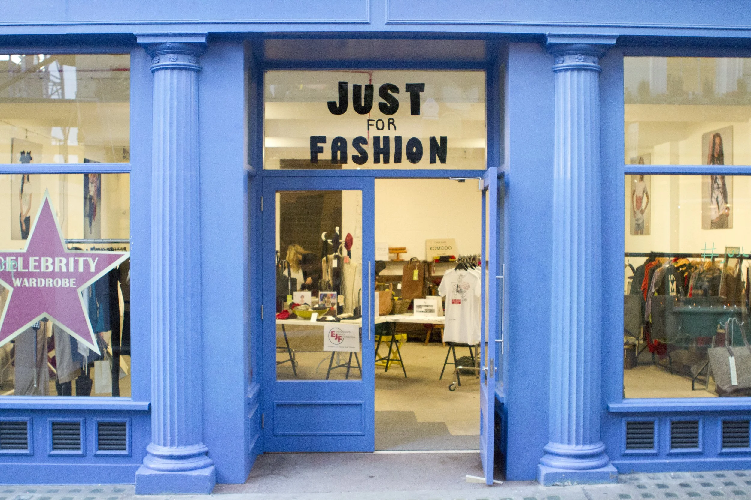Blue storefront with a sign reading 'Just for Fashion' and mannequins inside displaying clothing.