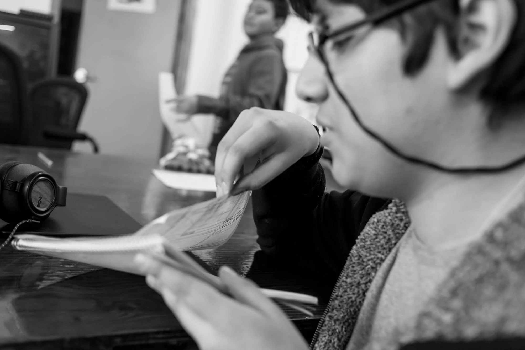 Sebastien flips through his script and story board as another participant walks by in the back ground. Sebastien was excited to come to the cartoon club and to develop his animation script about a sage trying to save the future. In this photo essay I show youth on the autism spectrum engaged in programming at Spectrum Productions. Spectrum Productions provides an opportunity for youth to gather together - they imagine, story board, write scripts, draw and create video while interacting with each other and with staff, something that is not always an easy task. 