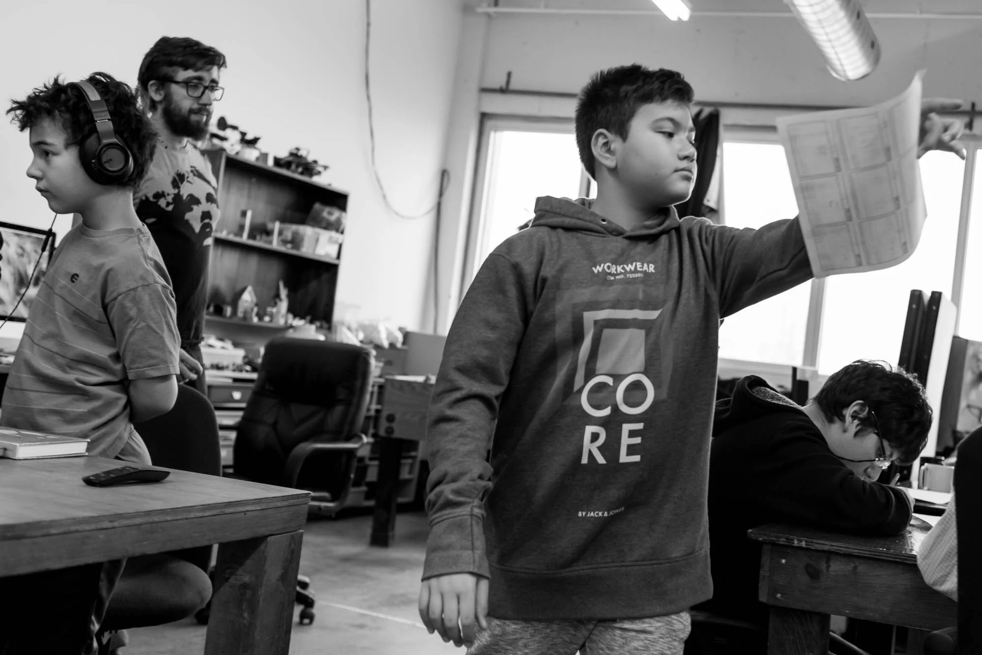 Raphael holds his story board up after receiving feedback on his work. Other participants continue their individual work in the background. In this photo essay I show youth on the autism spectrum engaged in programming at Spectrum Productions. Spectrum Productions provides an opportunity for youth to gather together - they imagine, story board, write scripts, draw and create video while interacting with each other and with staff, something that is not always an easy task. 