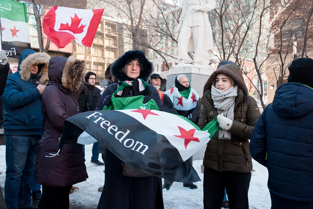 MONTREAL, March 18, 2018. -- Protesters wave flags at the 7th anniversary of the Syrian uprising at Place Norman-Bethune, Montreal. This uprising, which was initially peaceful led to a brutal civil war which still continues. 