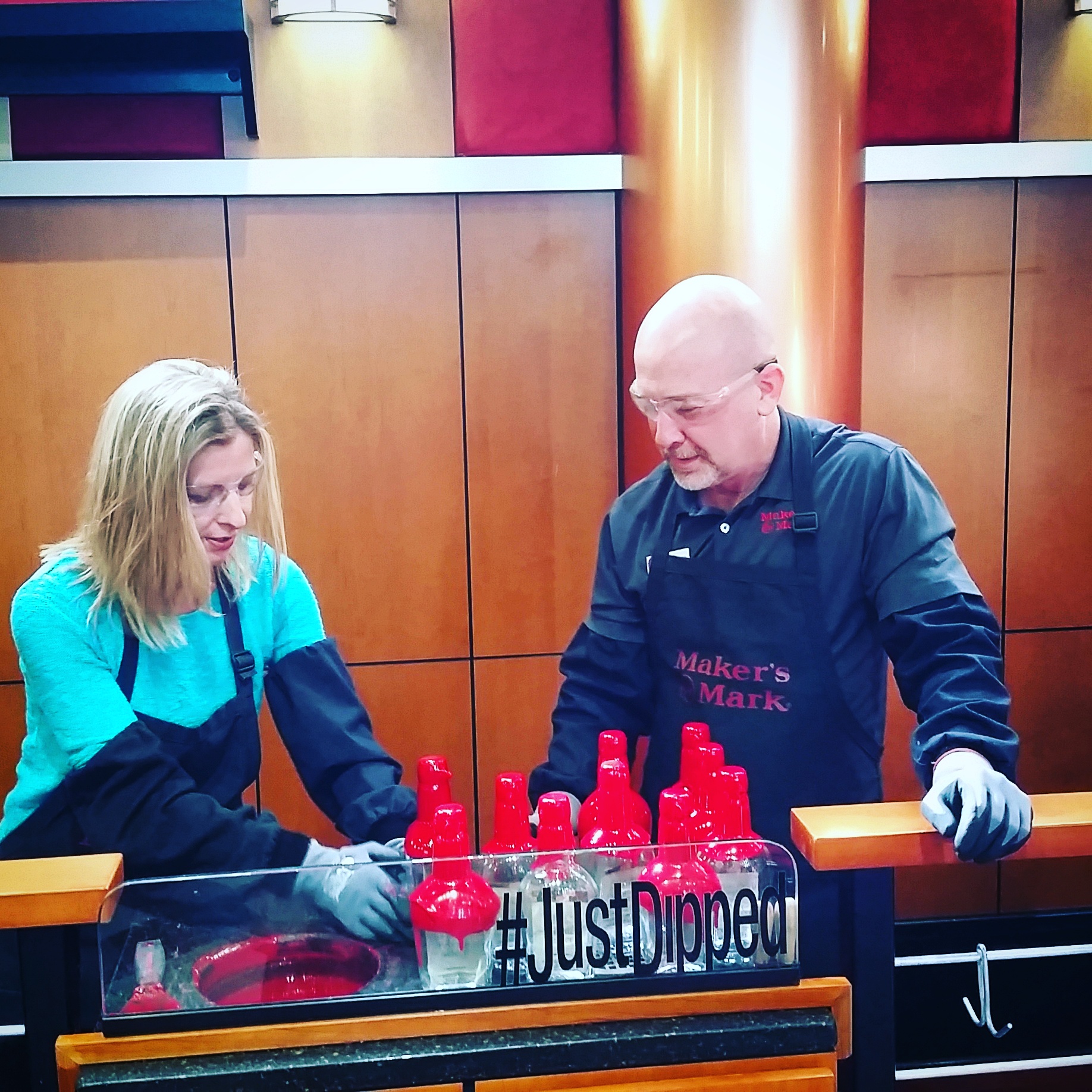 Dipping a bottle of Marker's Mark Bourbon into the signature red wax.