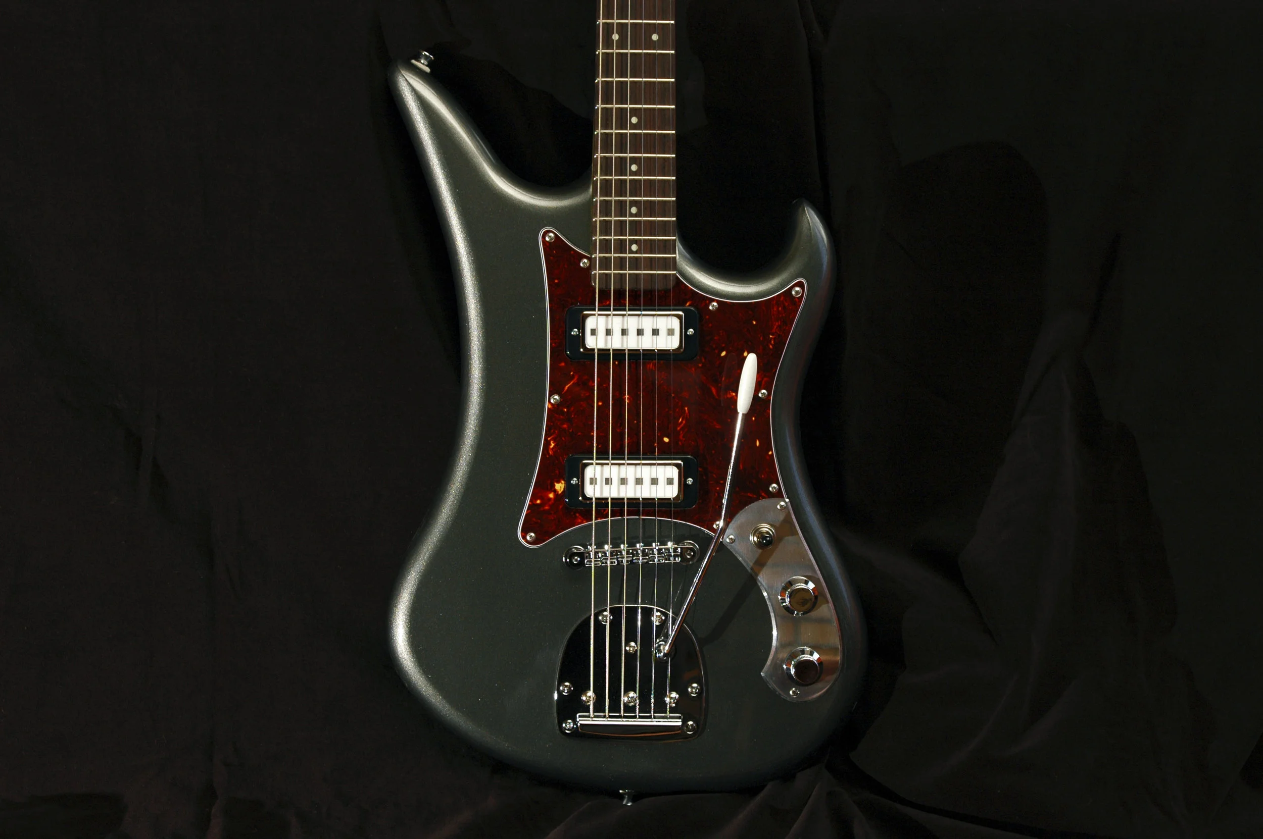 This is a Spectre in Graphite Metallic, a custom mixed color. The body is lightweight Alder and the neck is figured Maple with an Indian Rosewood fingerboard (25-1/2" scale.) The pickups are Square Pole Single Coils by Roadhouse Pickups . Similar in appearance to some original Teisco pickups, these have an aggressive presence that yields a sparkling clean tone and complex overdrive sounds. This guitar is a nimble hot rod that is set to rock!