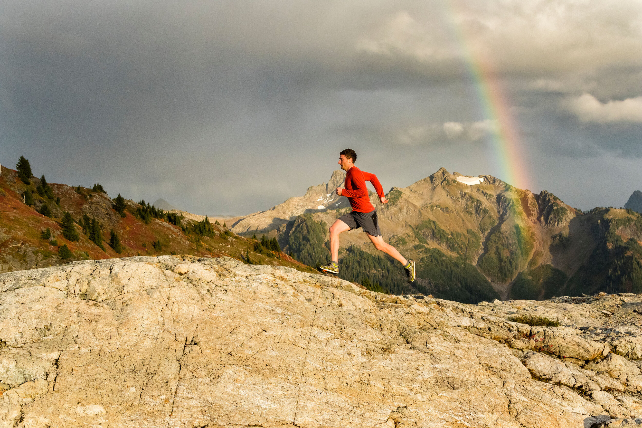  Adventure: Alex Aizenman trail running beneath a rainbow at Yellow Aster Butte in the North Cascades in autumn, Washington 