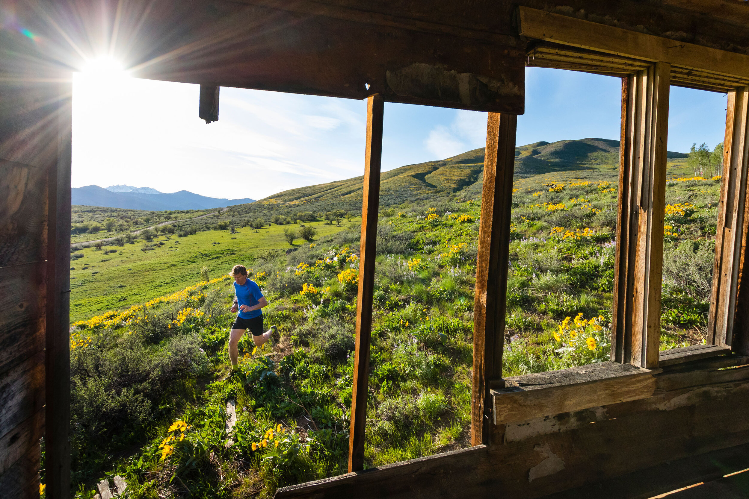  Adventure: Chris Solomon trail running past an old abandoned house in the Methow Valley in spring, Washington 