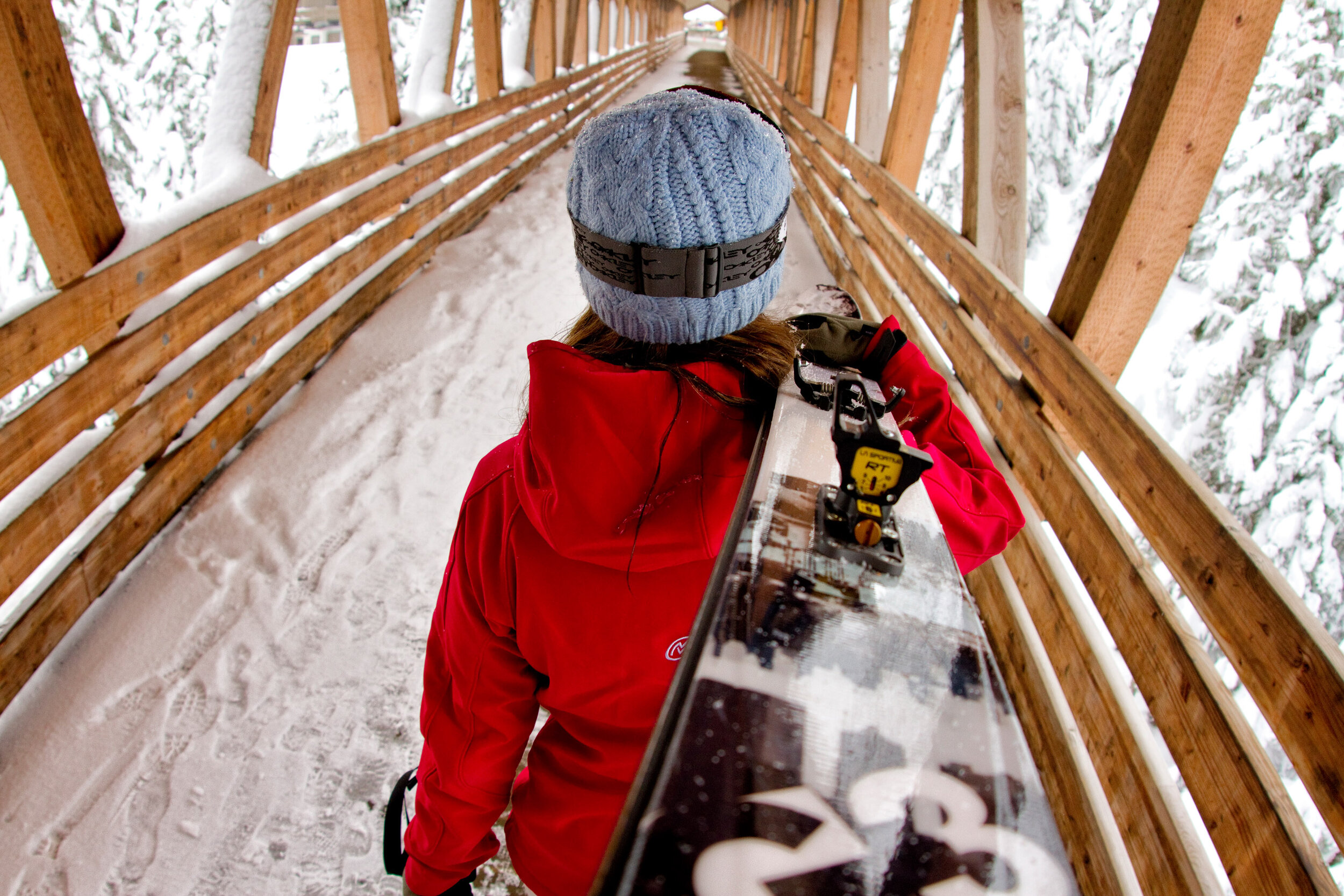  Lifestyle:  A young woman walking with her skis across the footbridge at the base of Alpental Ski Area, Central Cascades 