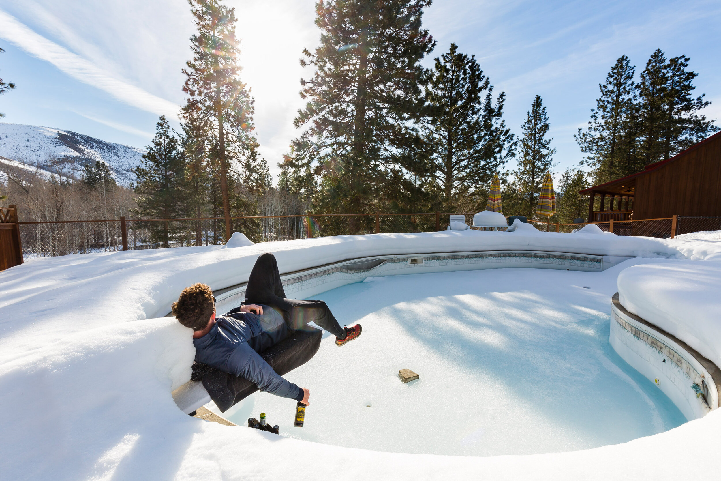  Lifestyle: Alex Aizenman sits on the diving board on a frozen outdoor pool in winter drinking a beer and waiting for summer, Winthrop, Washington 