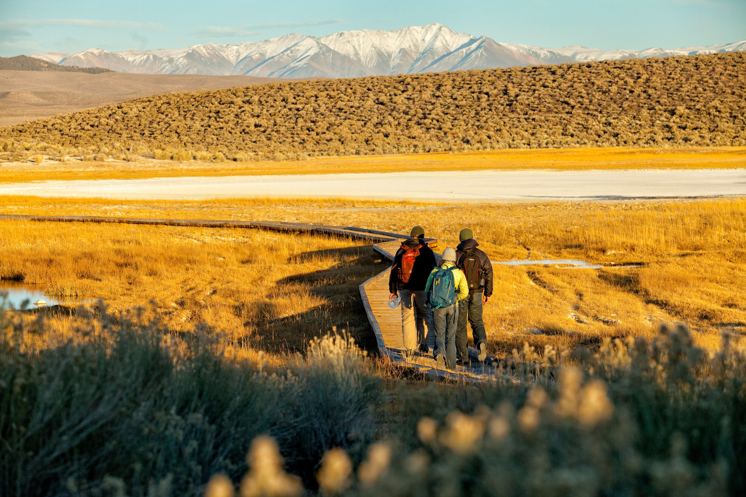  Lifestyle: Three friends walking to a natural hot springs at sunset, Owens Valley, Eastern Sierras, California 