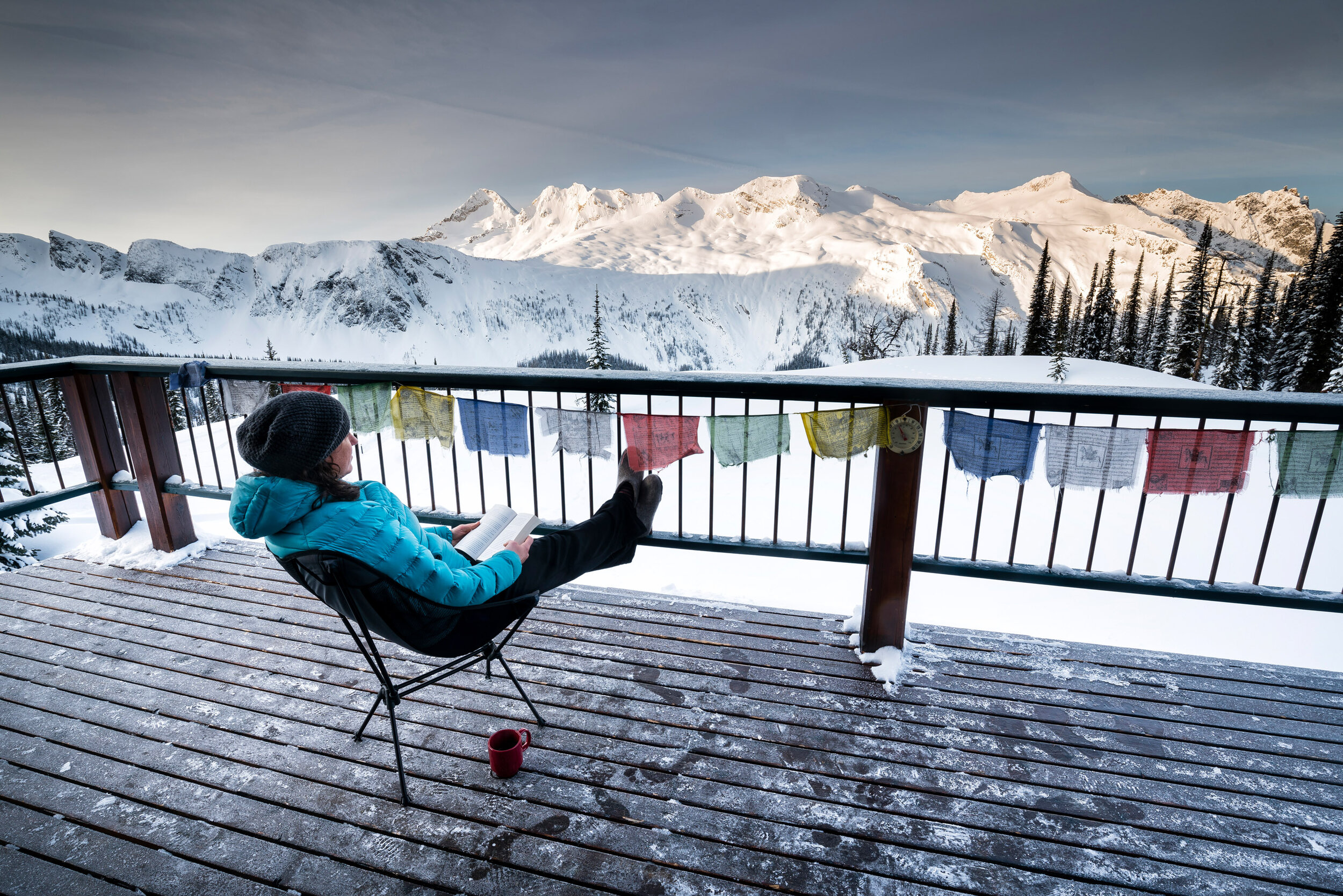  Lifestyle: Allison MacLeod looks out off the deck of a wilderness backcountry ski lodge in winter, Powder Creek Lodge, Purcell Mountains, British Columbia 