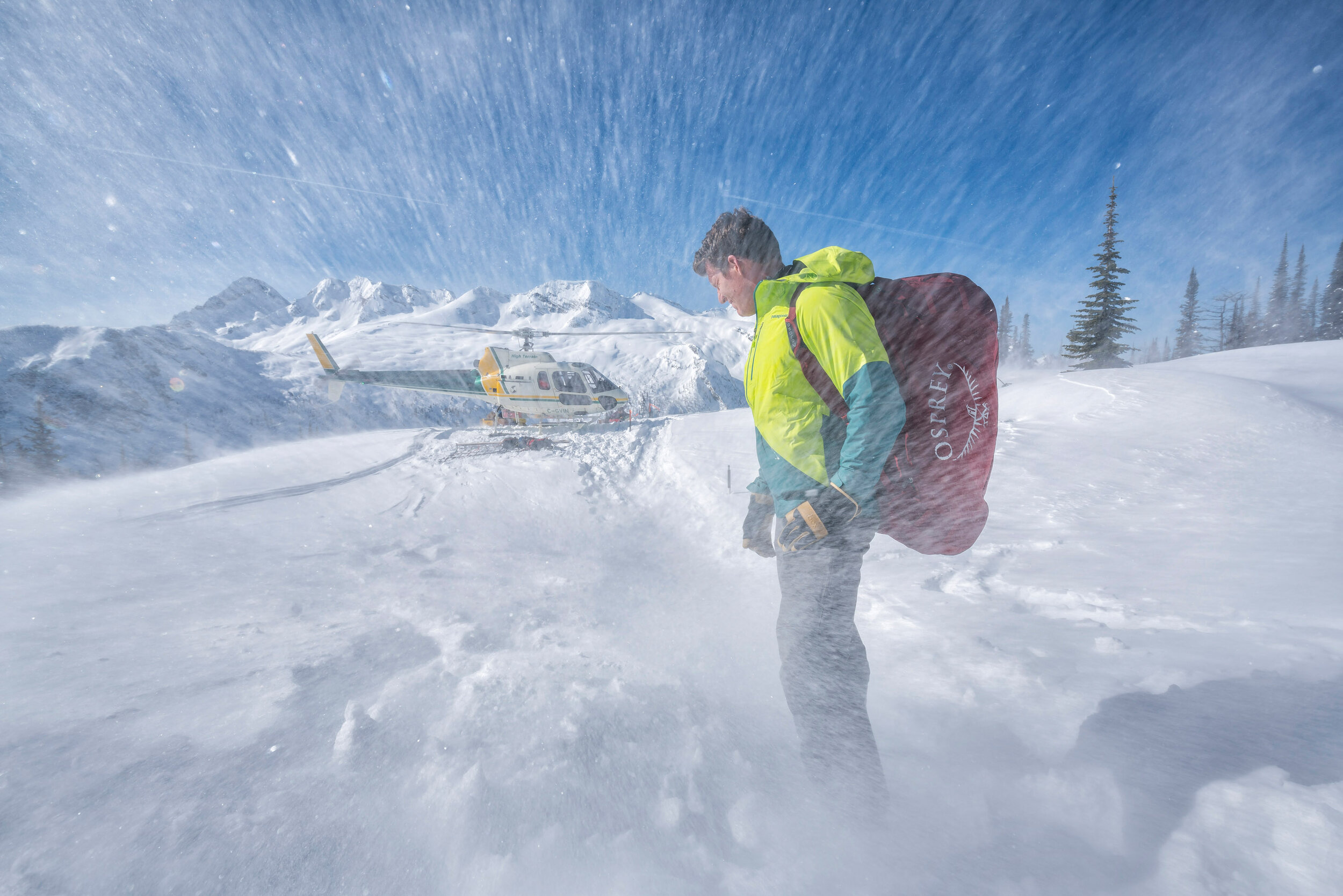  Adventure: Michael Hildebrand unloading a pack from the helicopter before a week long backcountry ski trip in the Purcell Mountains, British Columbia, Canada 