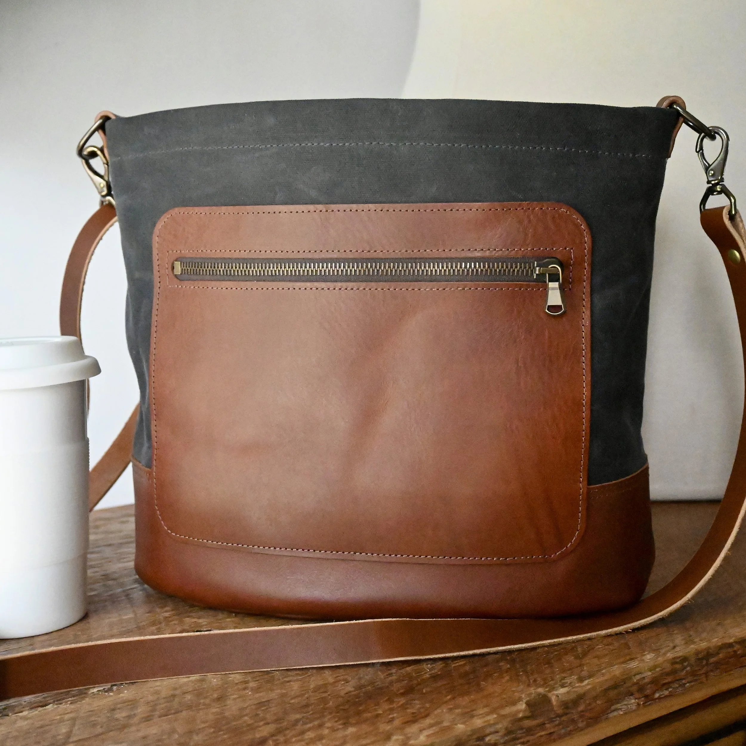 Graphite waxed canvas and brown leather crossbody Day Bag. The leather is slightly pebbled and the hardware is antique brass.