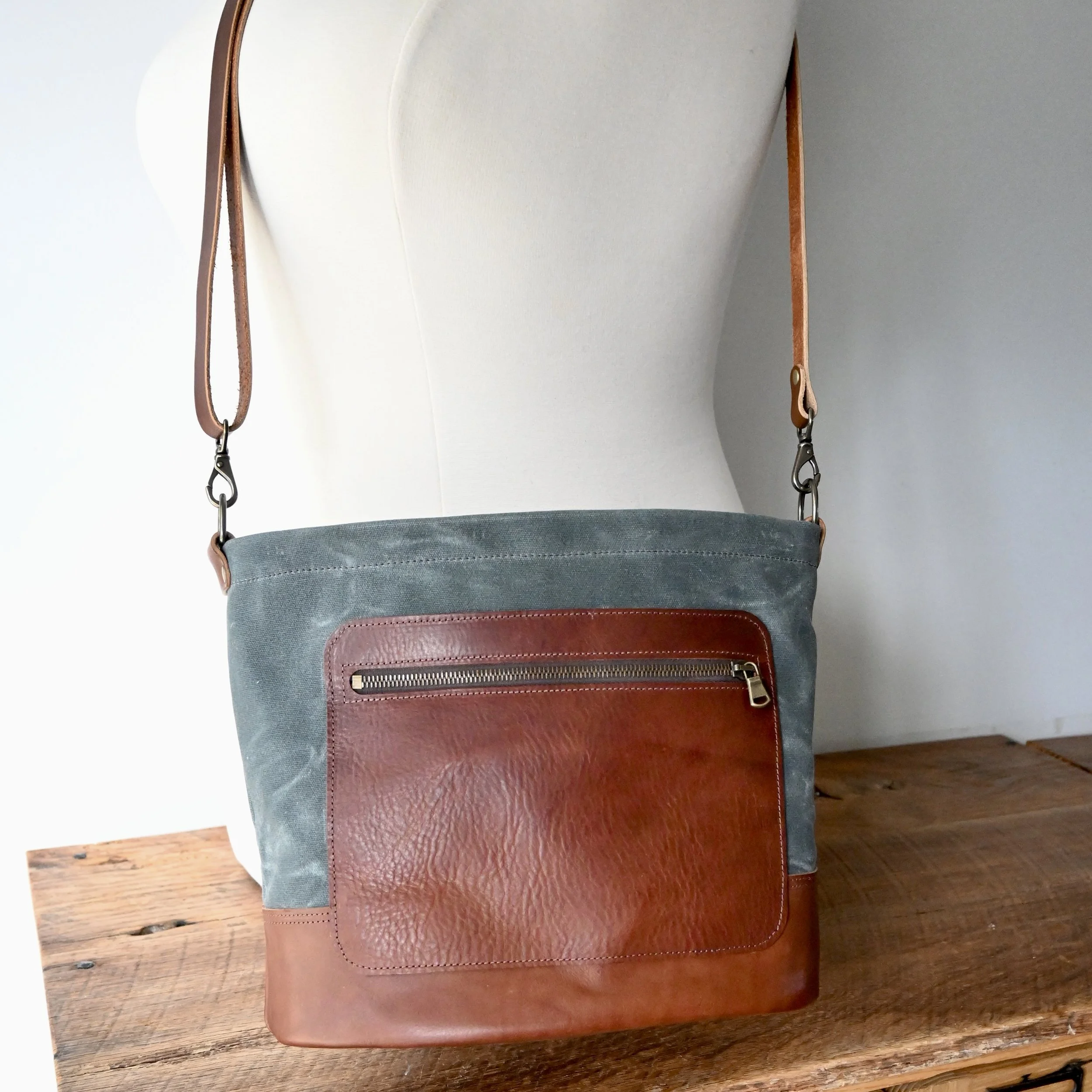 Stitich & Rivet Day Bag shown cossbody on a mannequin. The bag has brass hardware and the leather is lightly pebbled.