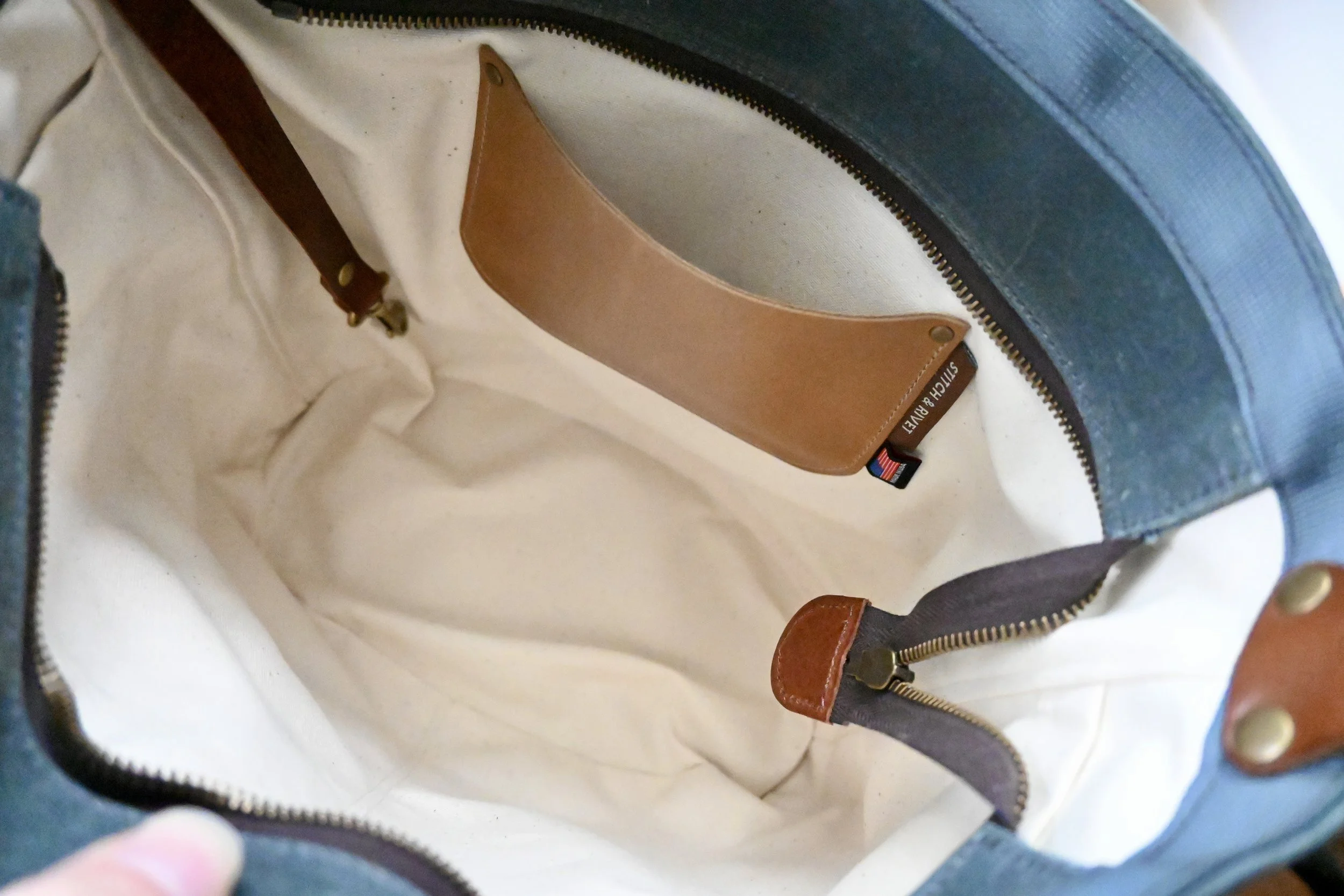 Interior pocket of waxed canvas and leather day bag. The image shows the small leather pocket on the interior.