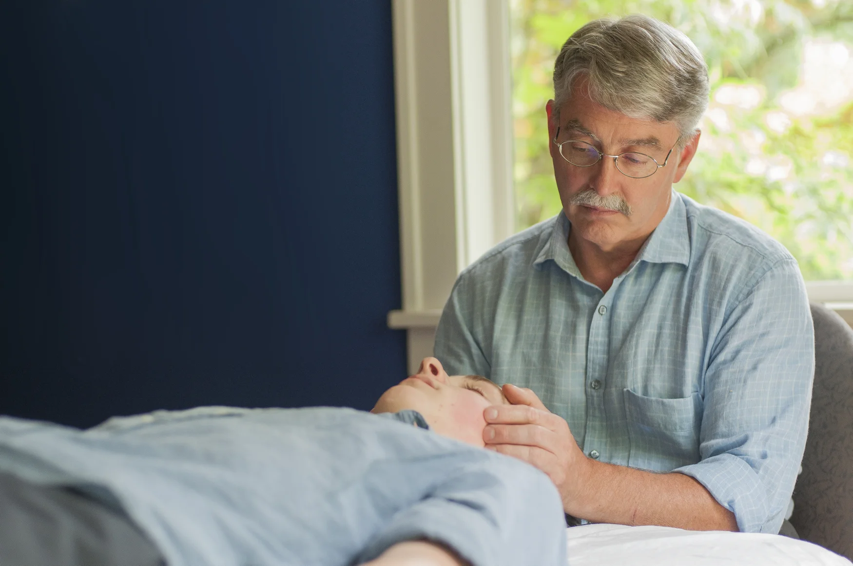 Dr. Hall is doing cranial work to assess a patient's physical symptoms. A series of consecutive cranial treatments successfully alleviated the patient's longstanding discomfort.
