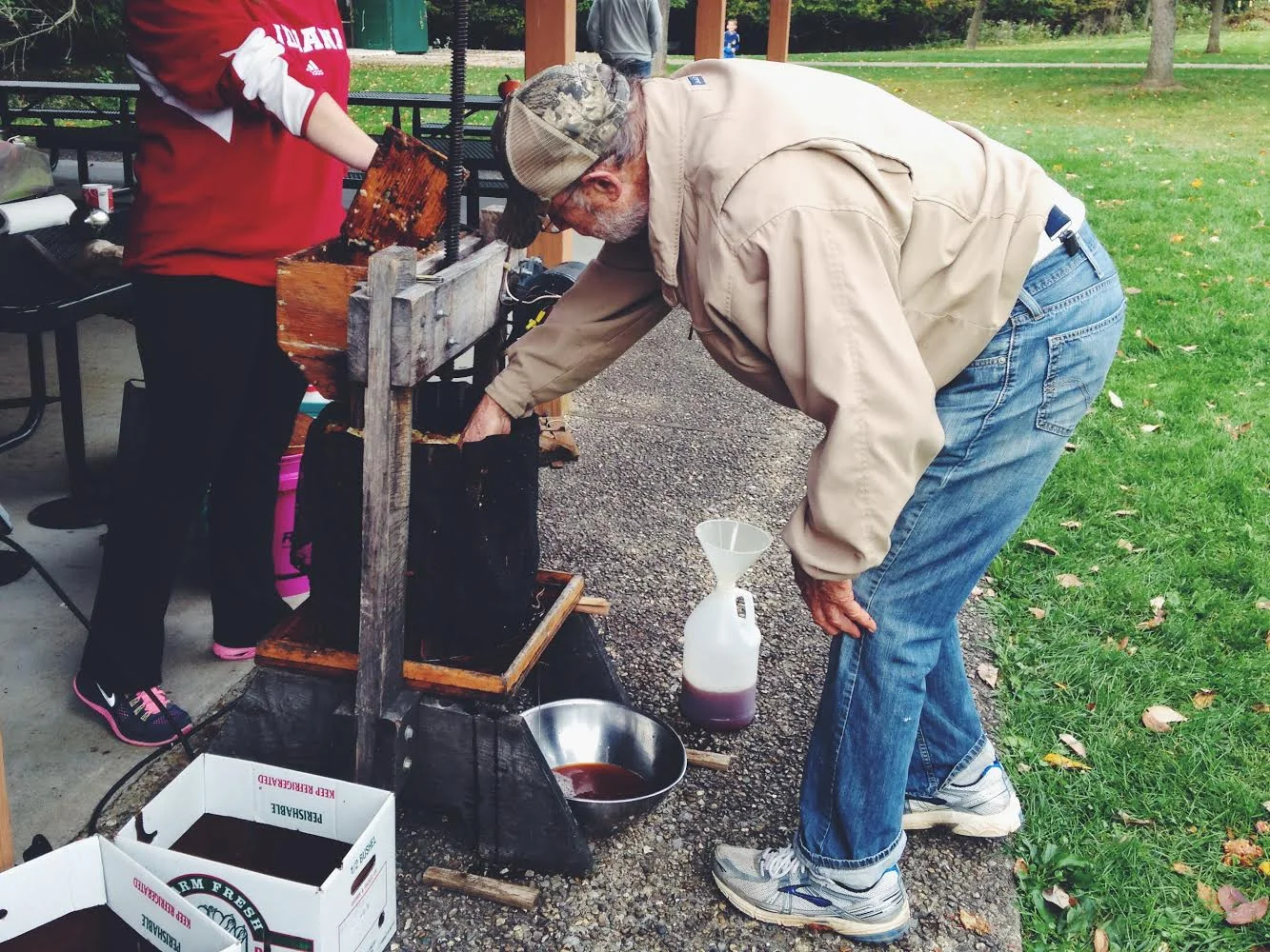 Volunteers keep the cider press running nonstop. The cider is then warmed, & volunteers fill their mugs before walking around the orchard.