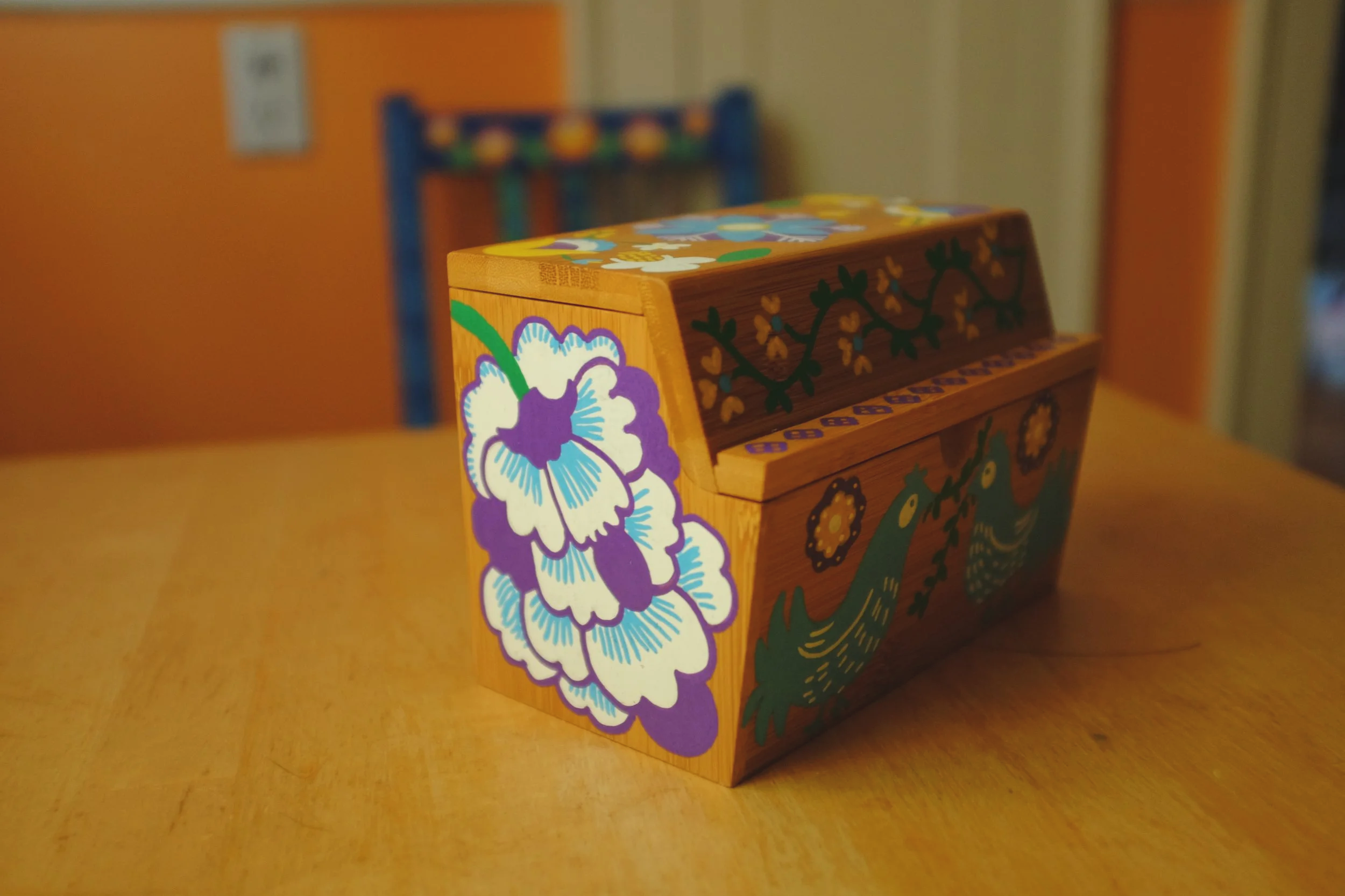 a wooden box with bright designs of birds and flowers