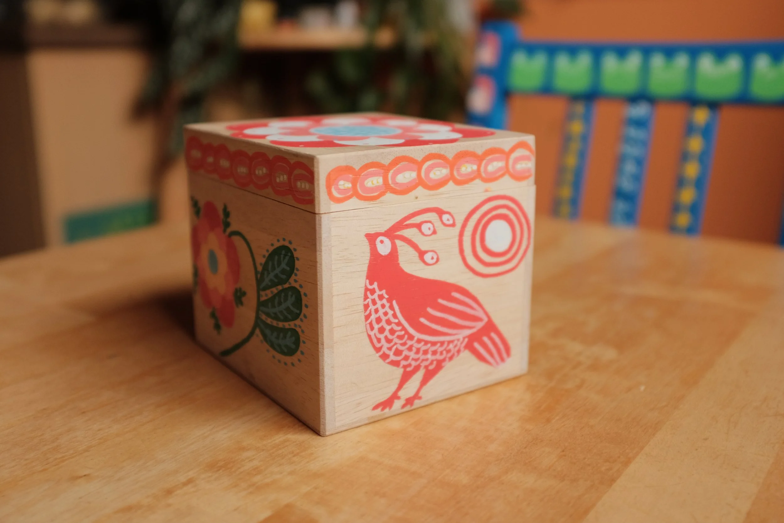 a pale wooden box with brightly coloured designs