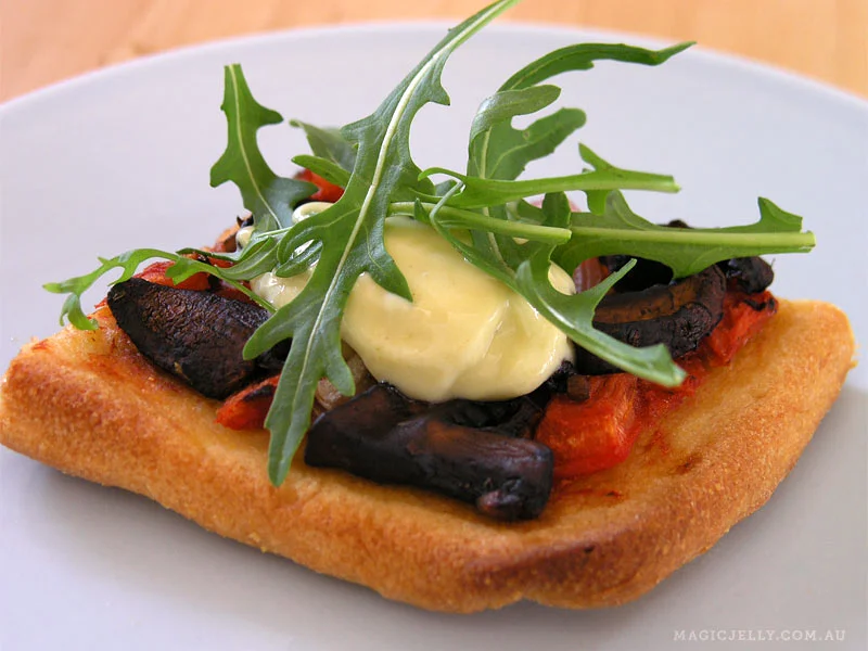 Cornmeal crust pizza. Mushrooms sauteed with garlic & balsamic vinegar, homemade lemony aioli & fresh rocket.
