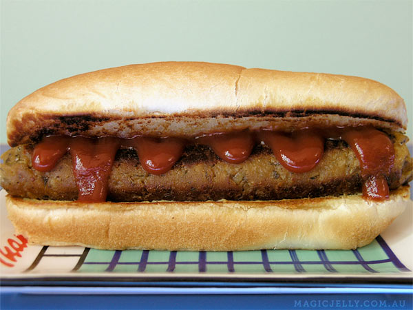 Homemade chickpea seitan sausage with loads of sauce on a hotdog bun.