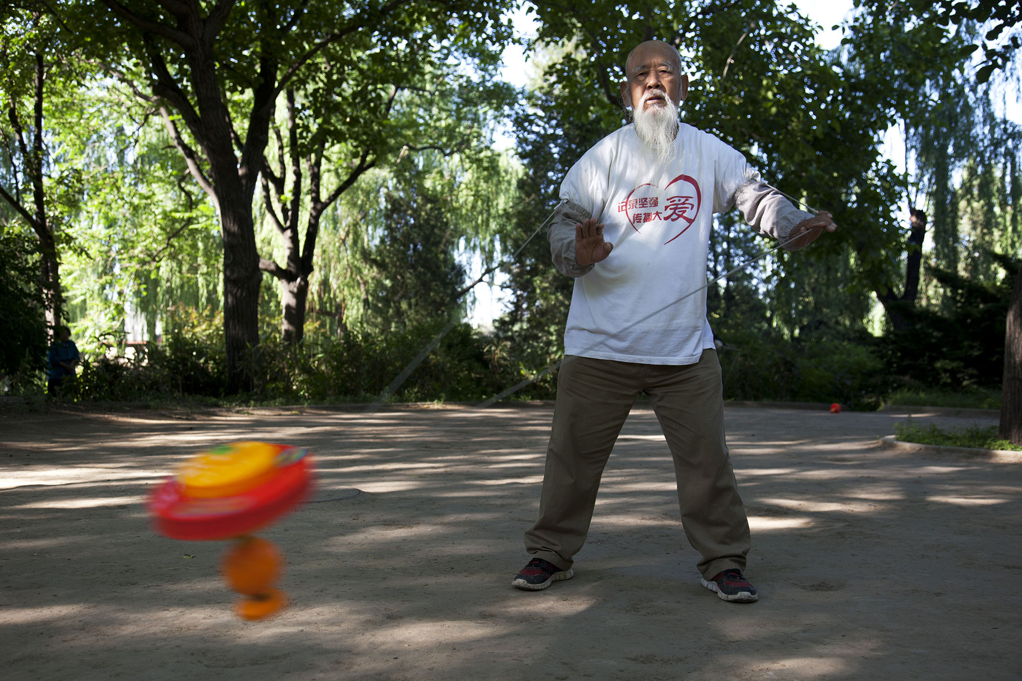  Man takes his morning exercise by turning a spinning top in Zizhuyuan Park. 